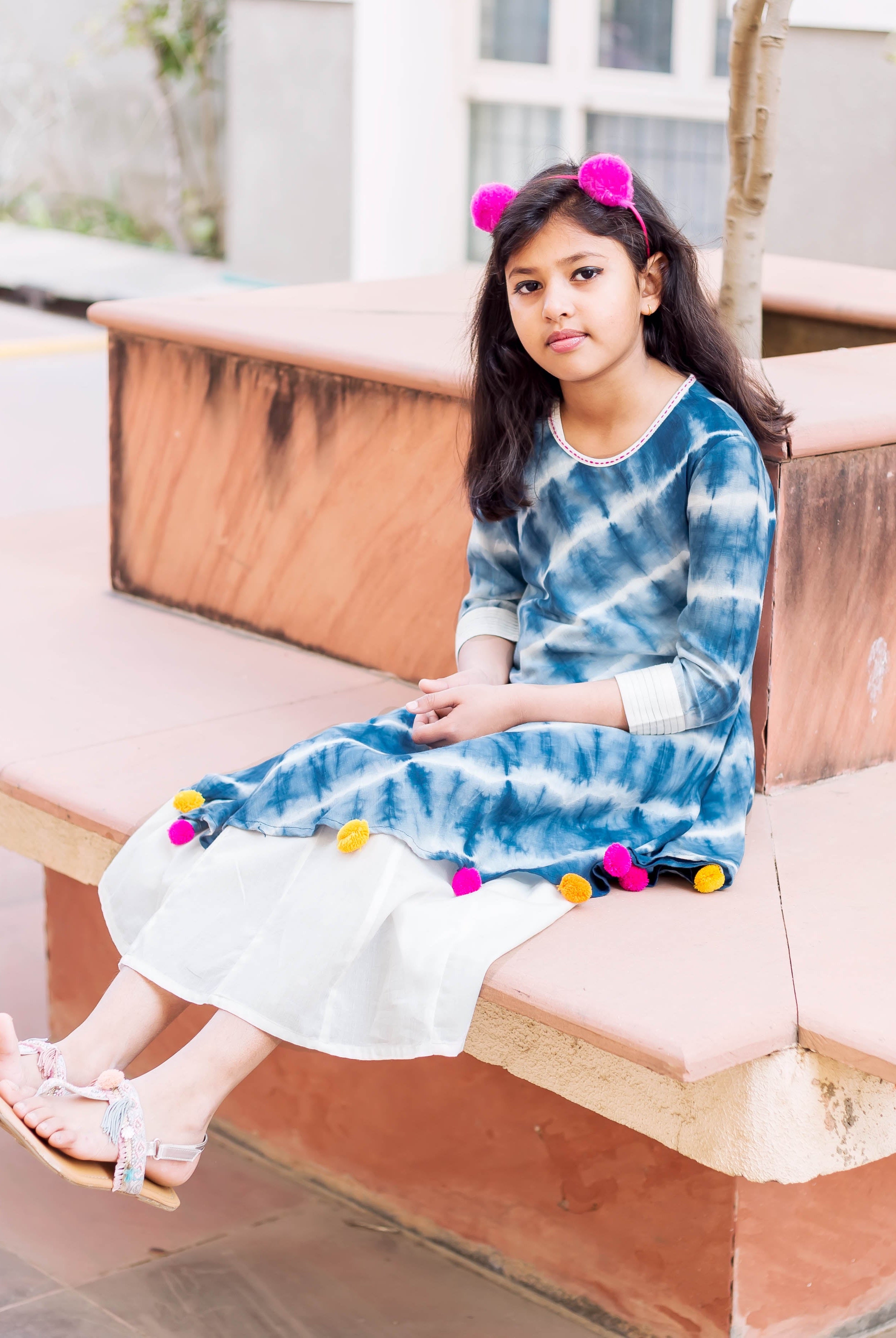 Front full look: young model in blue and white tie-dye asymmetrical kurta dress with colorful tassels.