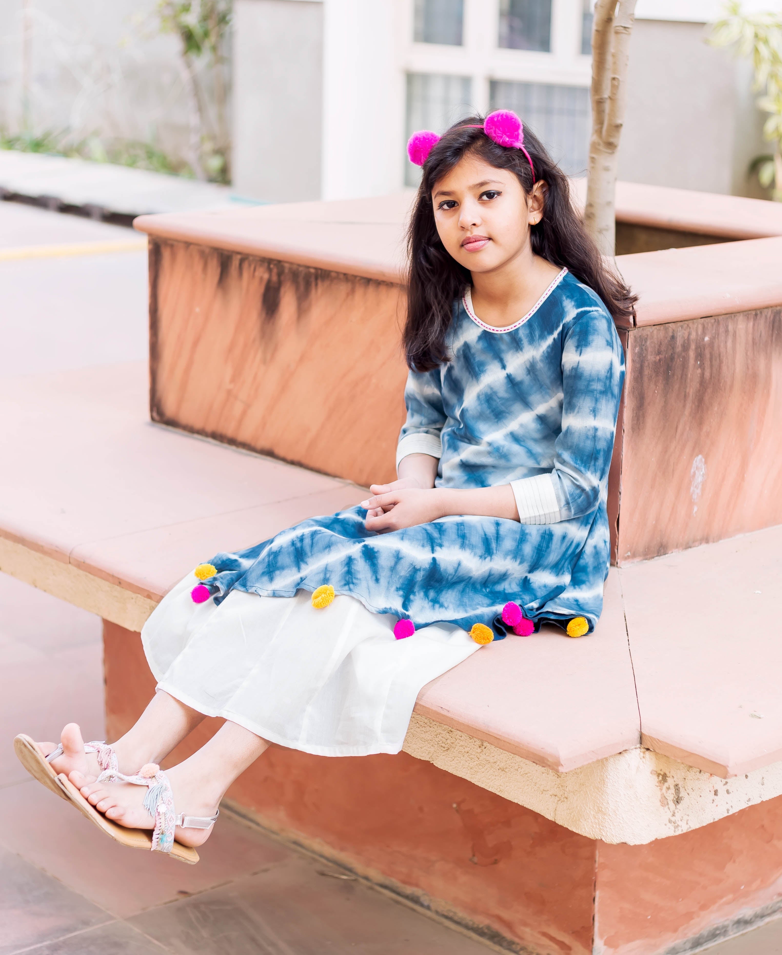 Front full look: young model in blue and white tie-dye asymmetrical kurta dress with colorful tassels.