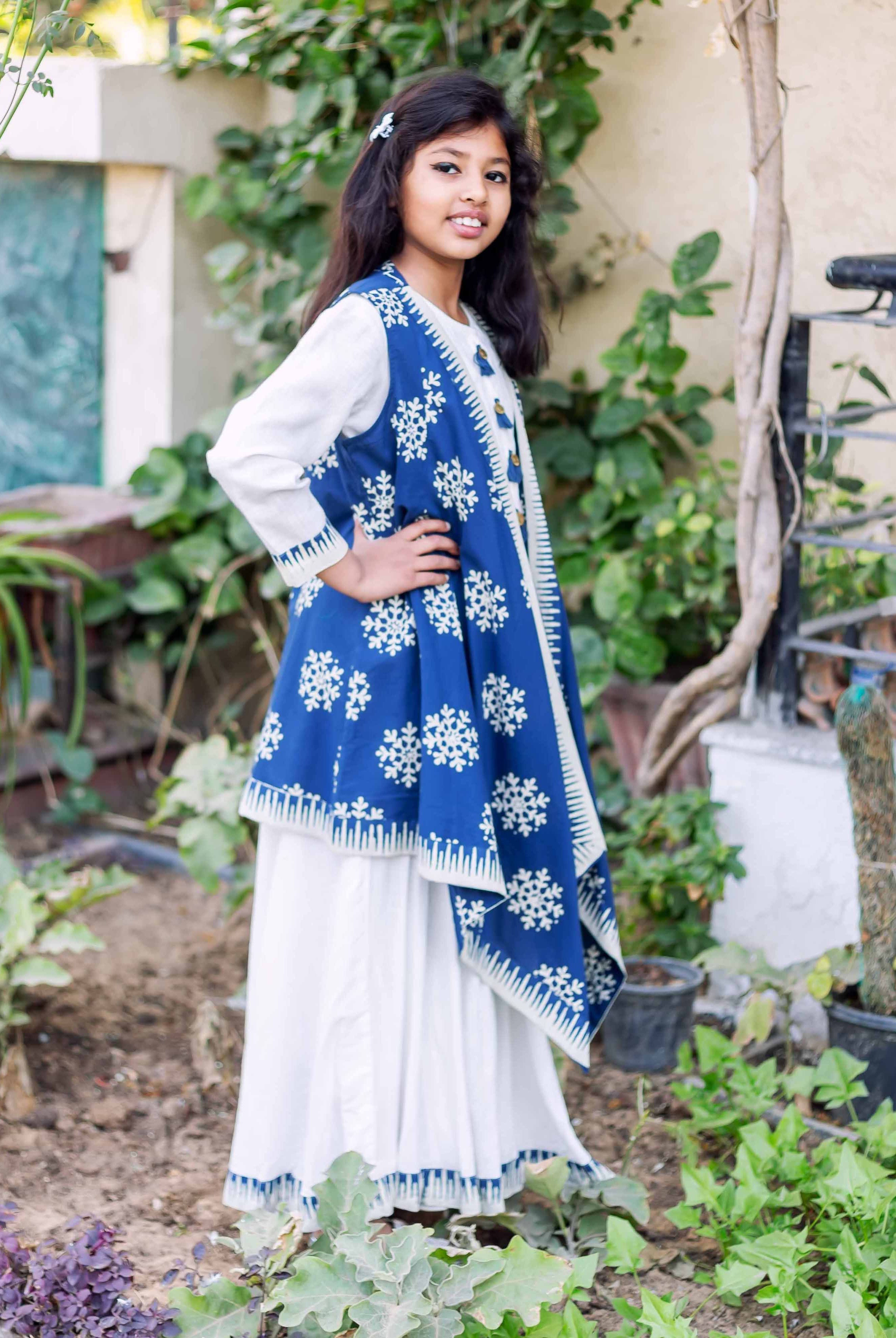 Young girl models floor-length white dress with indigo blue hand-block printed snowflake asymmetrical shrug.