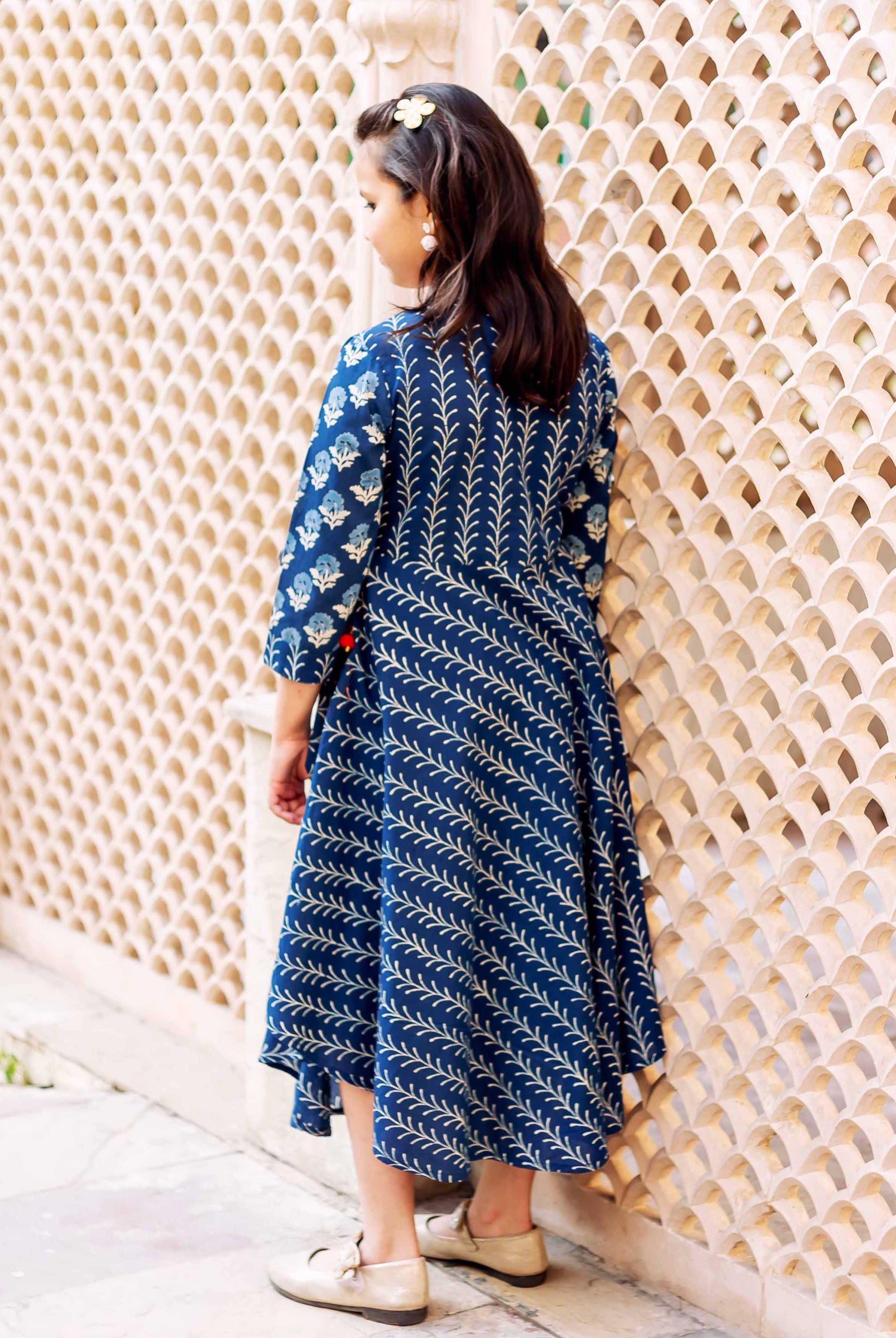 Young girl's back in blue hand-block printed asymmetrical dress with floral and leaf prints.