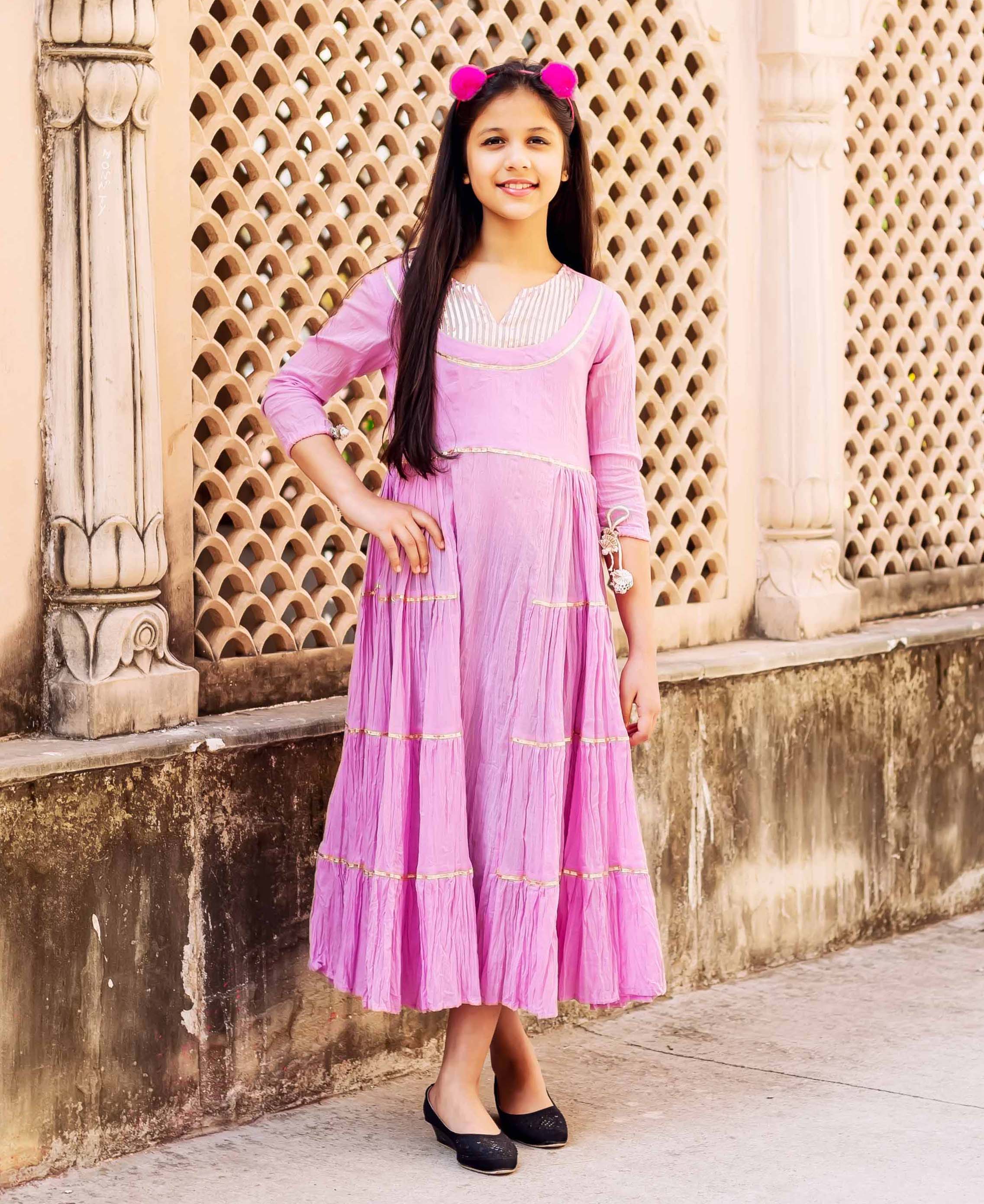 Pink frill long dress with gold trim on a young girl with long dark hair.