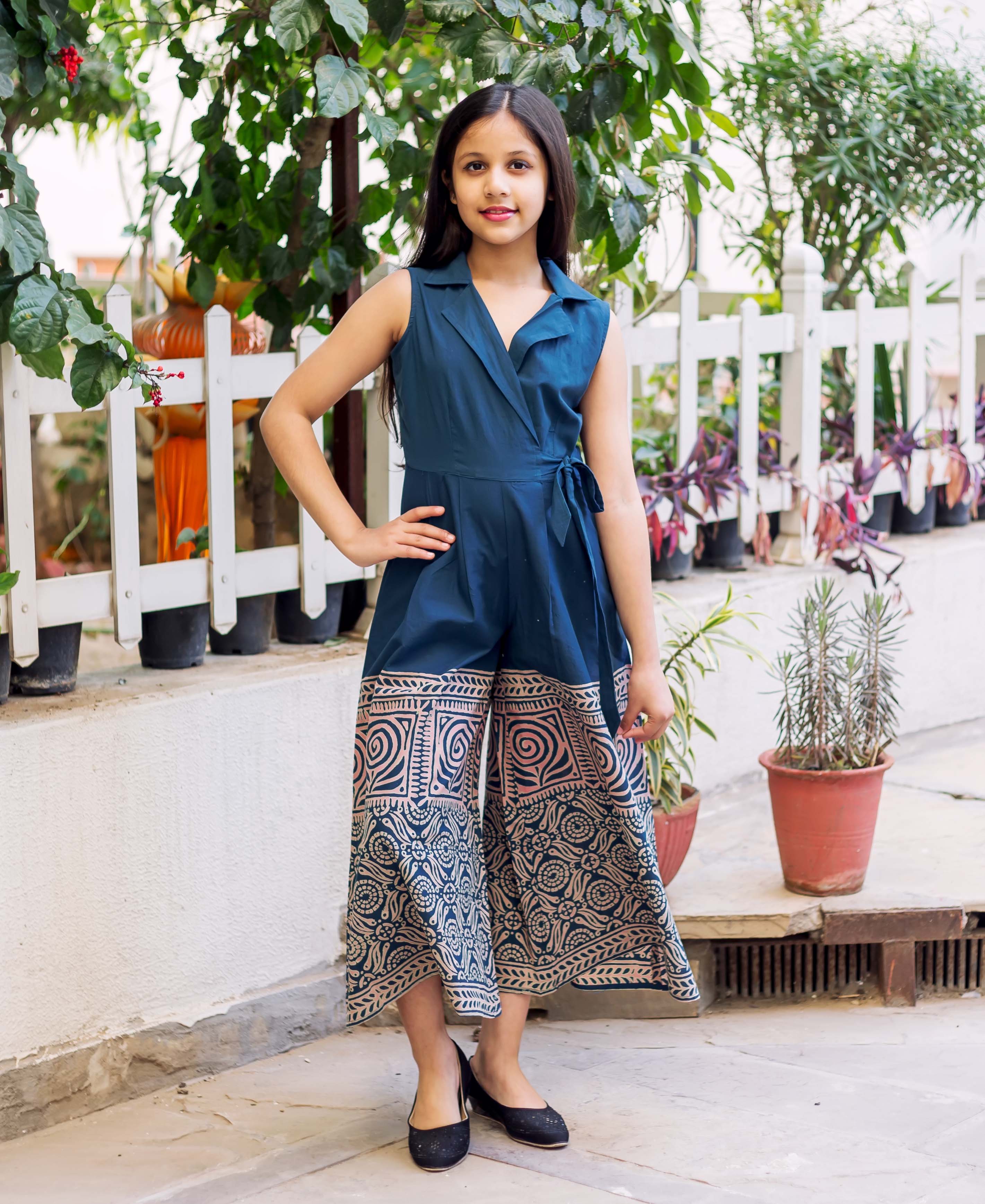 Young girl models an indigo blue sleeveless jumpsuit with hand-block printed wide-leg pants.