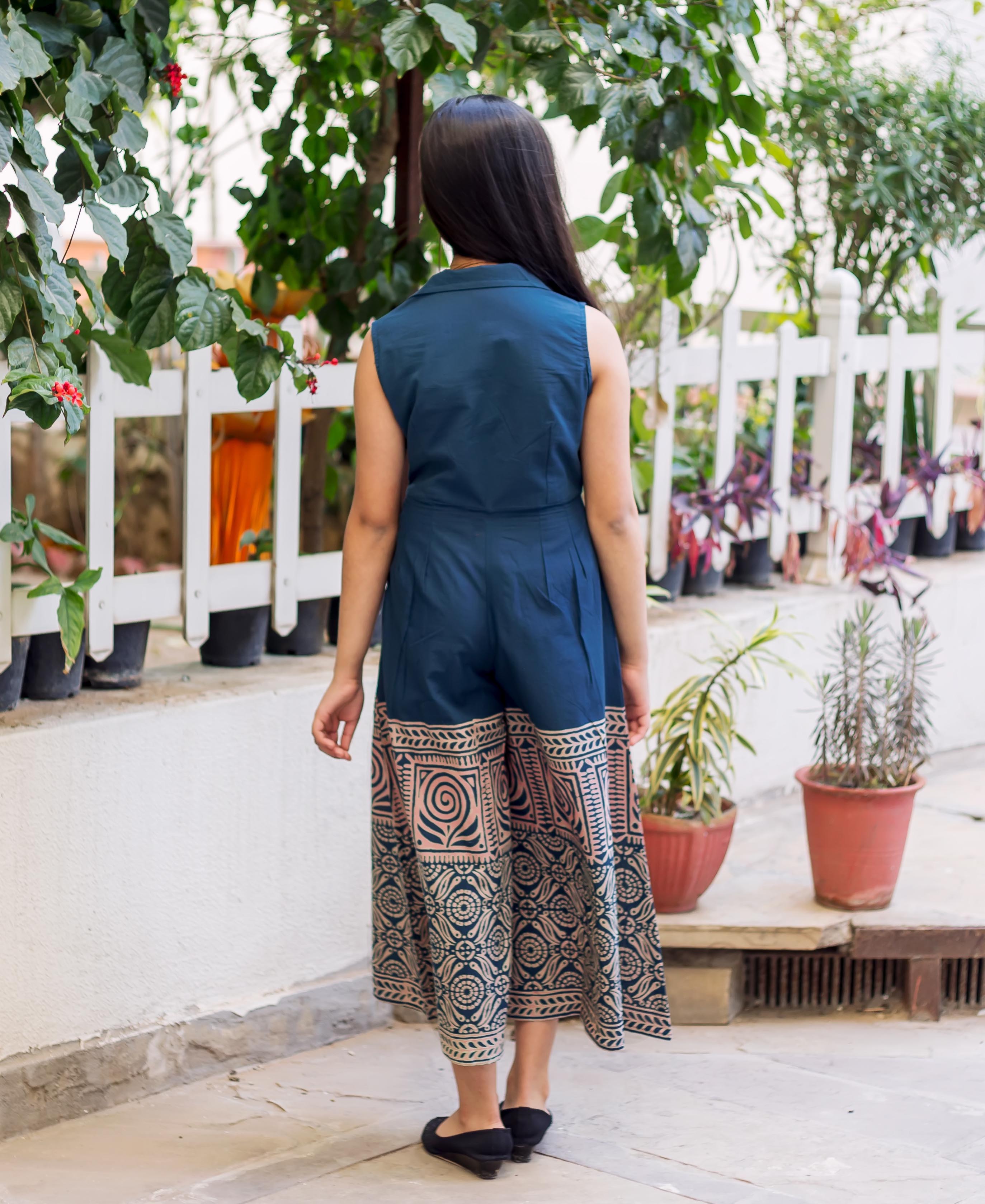A model wearing a blue and white hand-block-printed jumpsuit, facing away from the camera.