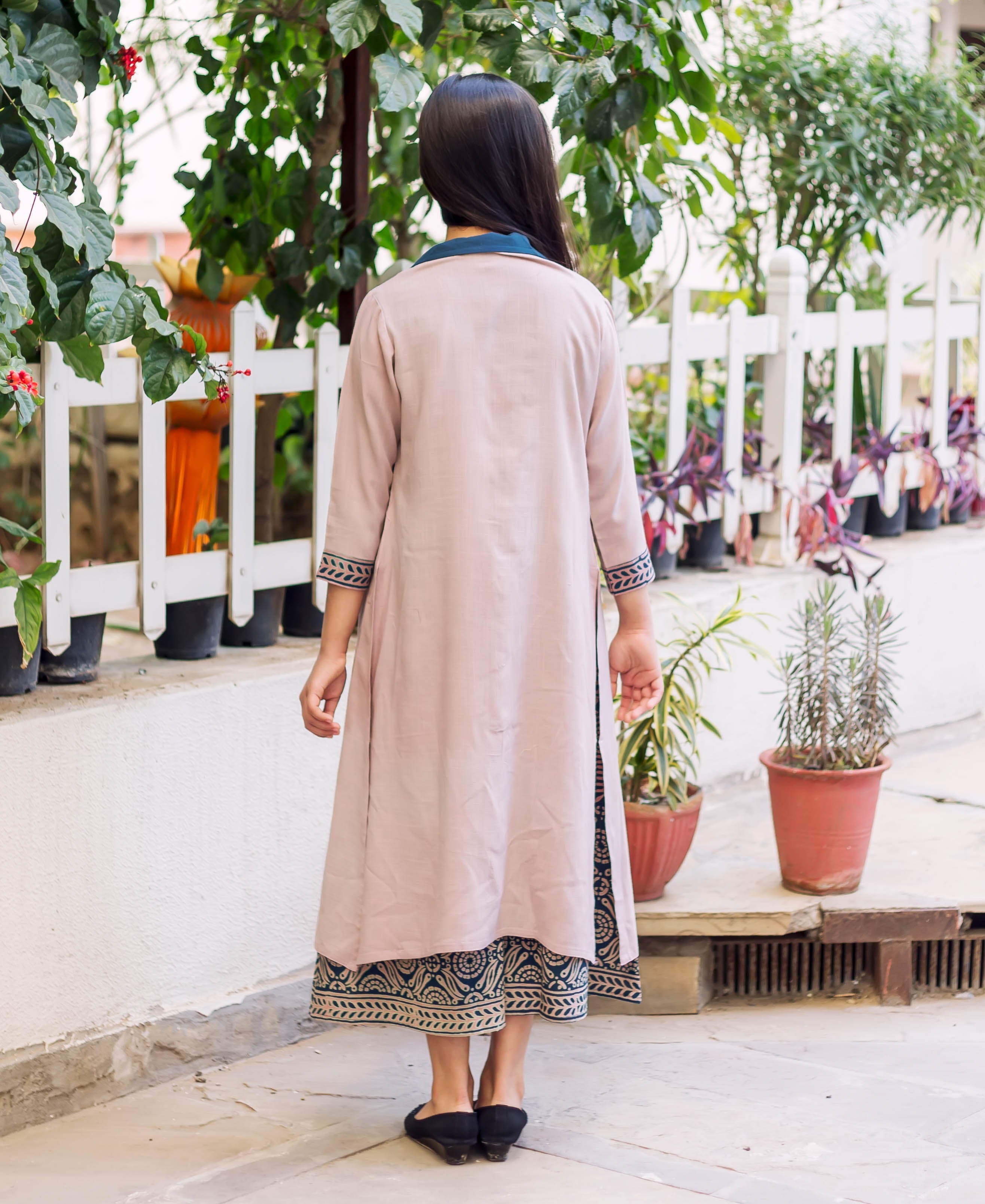 Back view model wearing full light pink jacket over dark blue hand-block printed dress.