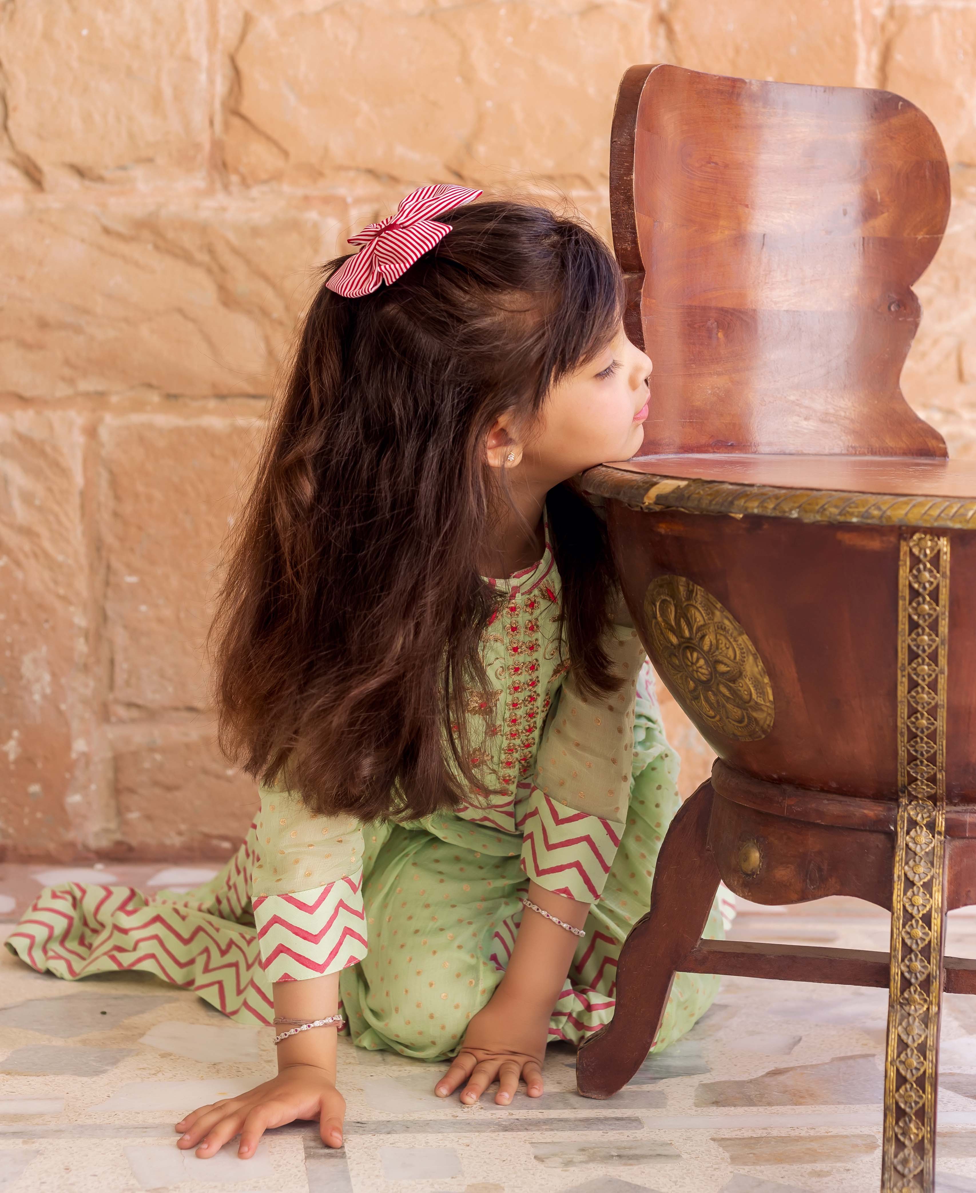 Mint green hand-block printed anarkali dress on a girl with red polka and zigzag designs.