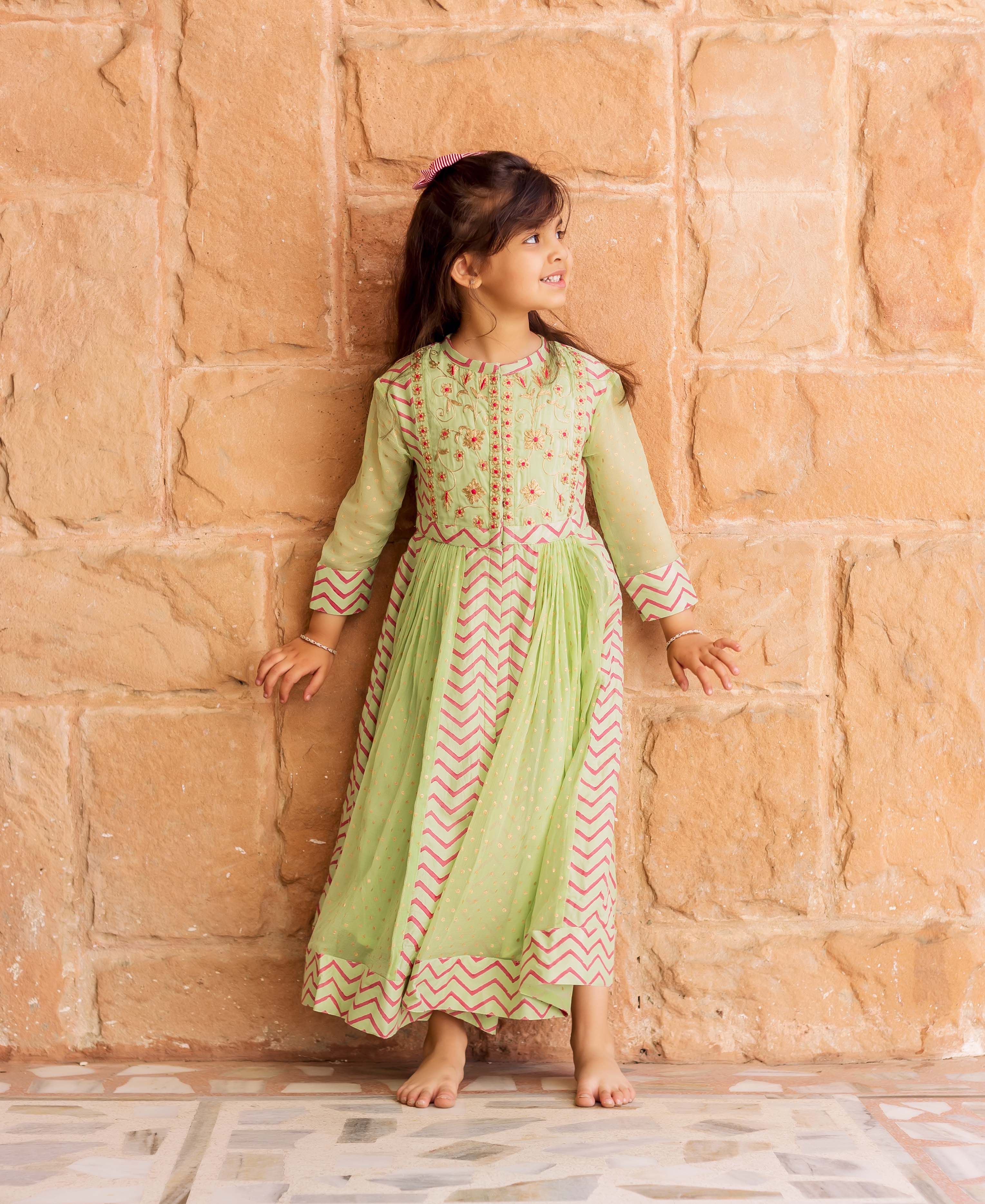 Baby girl in mint green hand-block-printed Anarkali dress with floral and chevron patterns.