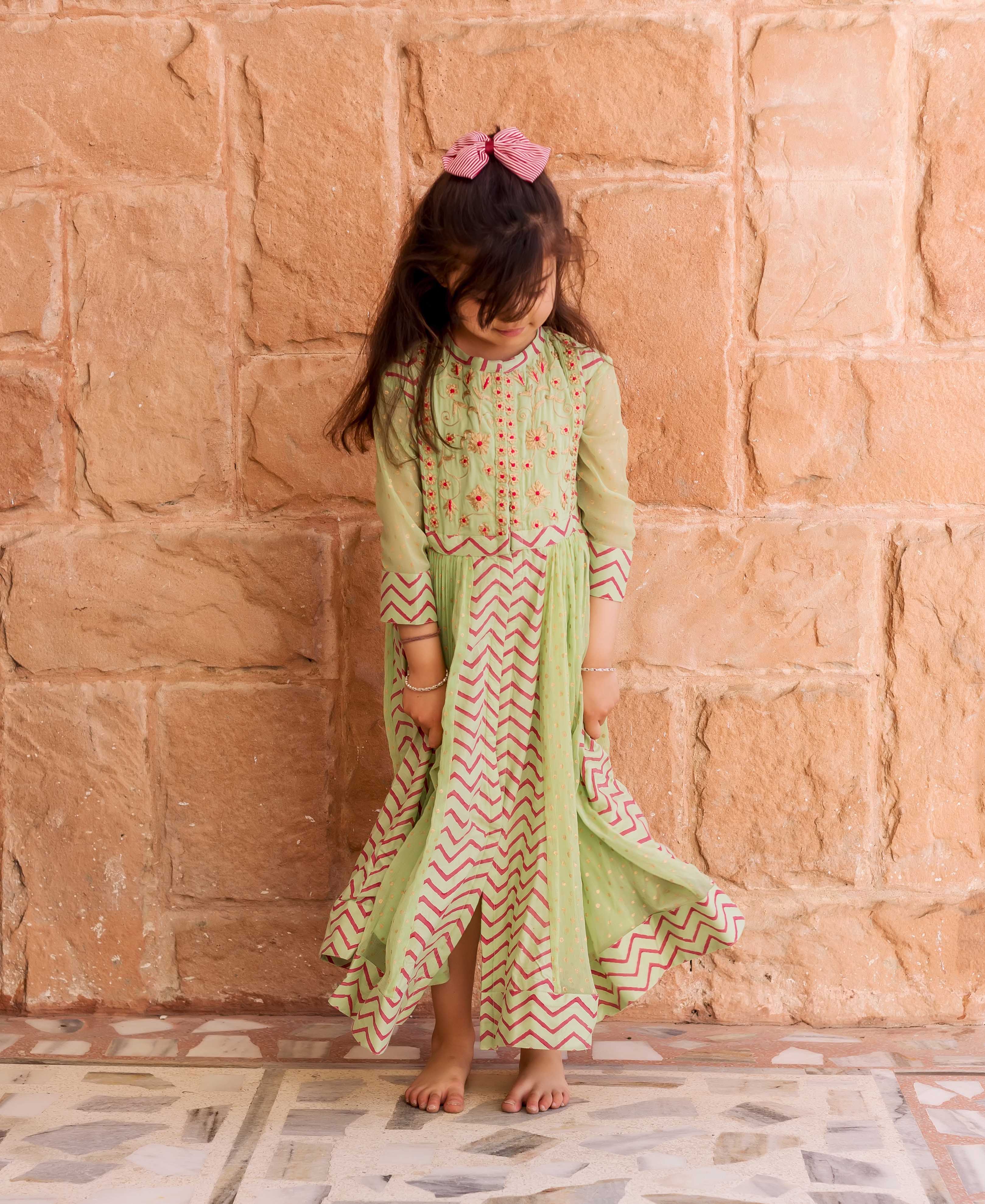 Mint green chiffon Anarkali dress with red hand-block-printed zigzag pattern worn by a young girl.