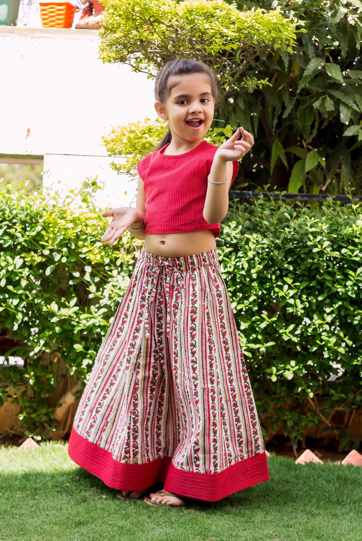 Young girl modeling a red cropped top with white and red block printed palazzo pants.