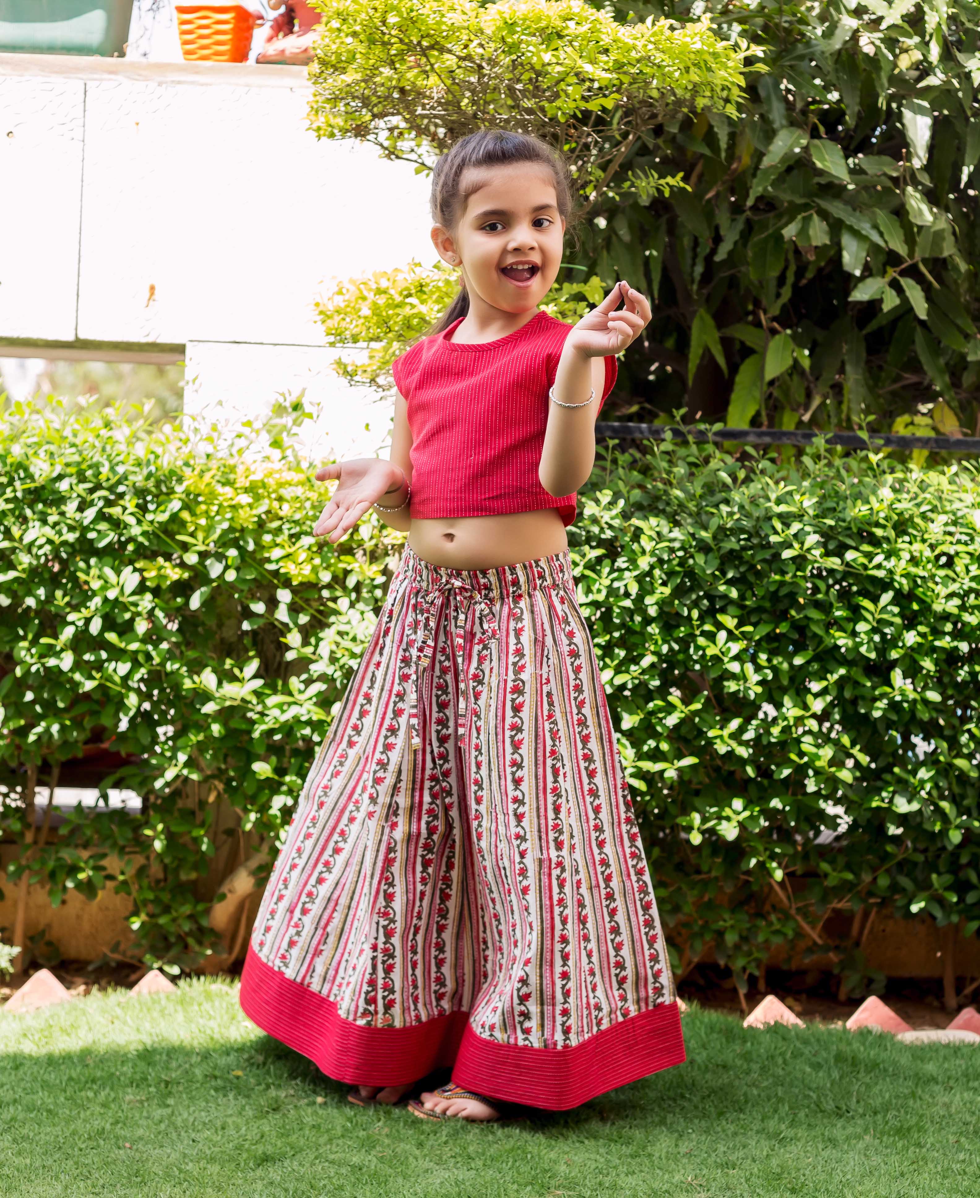 Young girl modeling a red cropped top with white and red block printed palazzo pants.