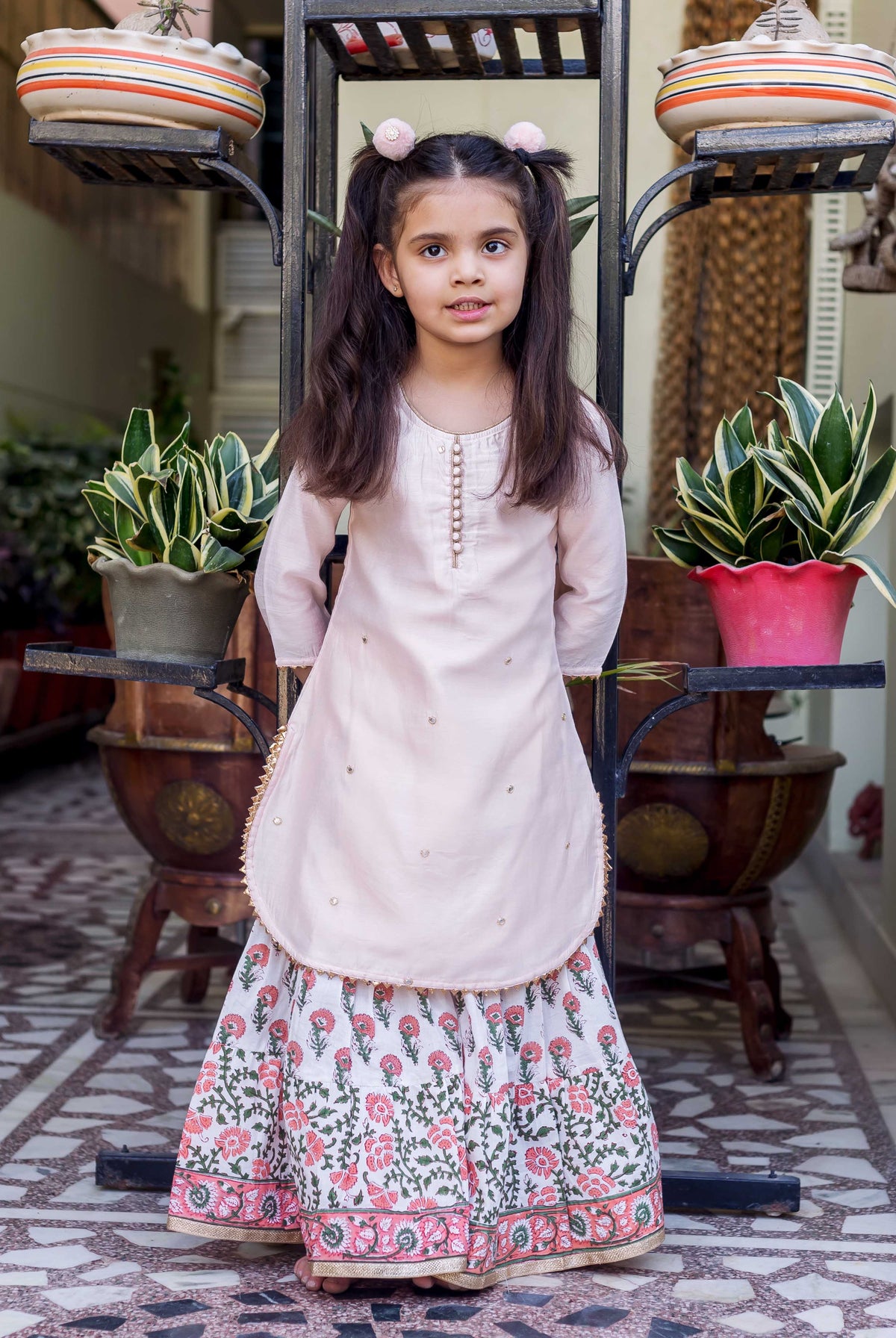 Pink embroidered straight short kurta with white and pink printed sharara on a young girl.