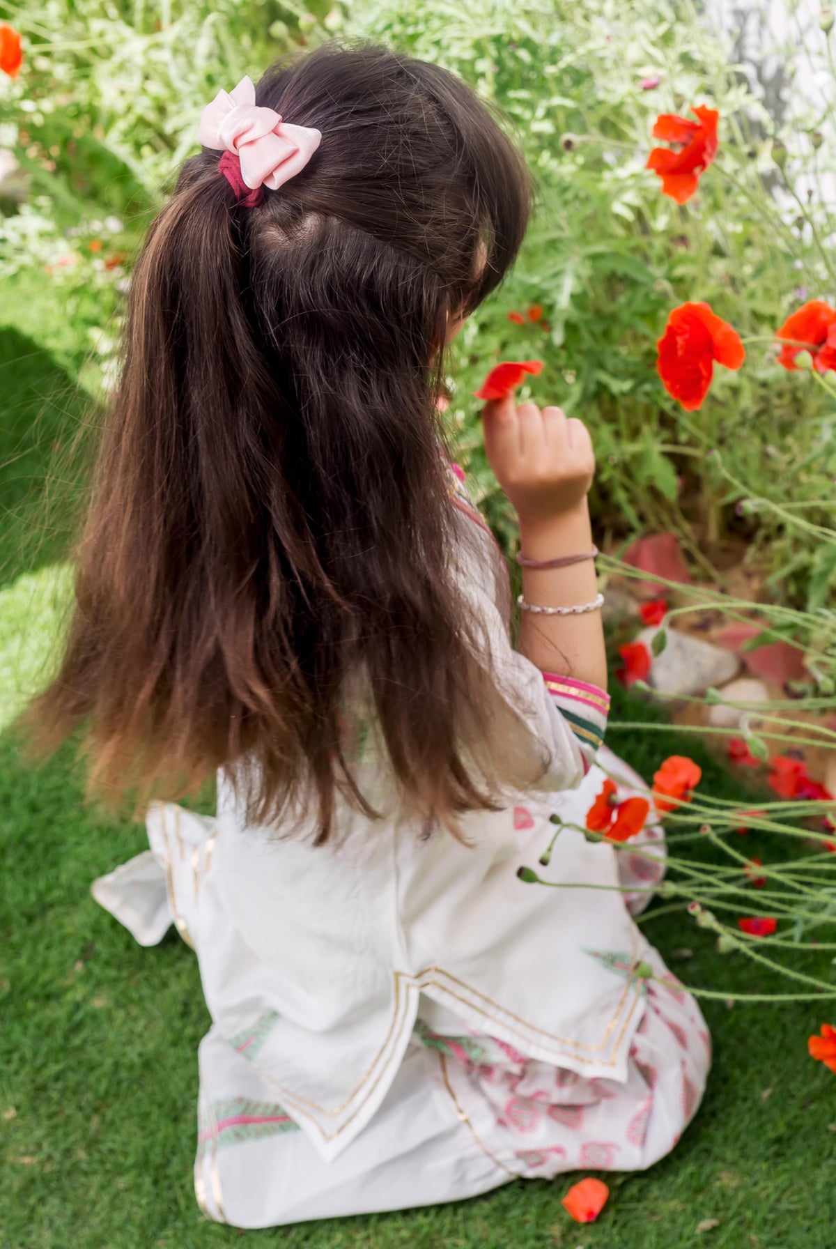 Young girl from behind in a white Chanderi hand-block printed ethnic piece with pink motifs.