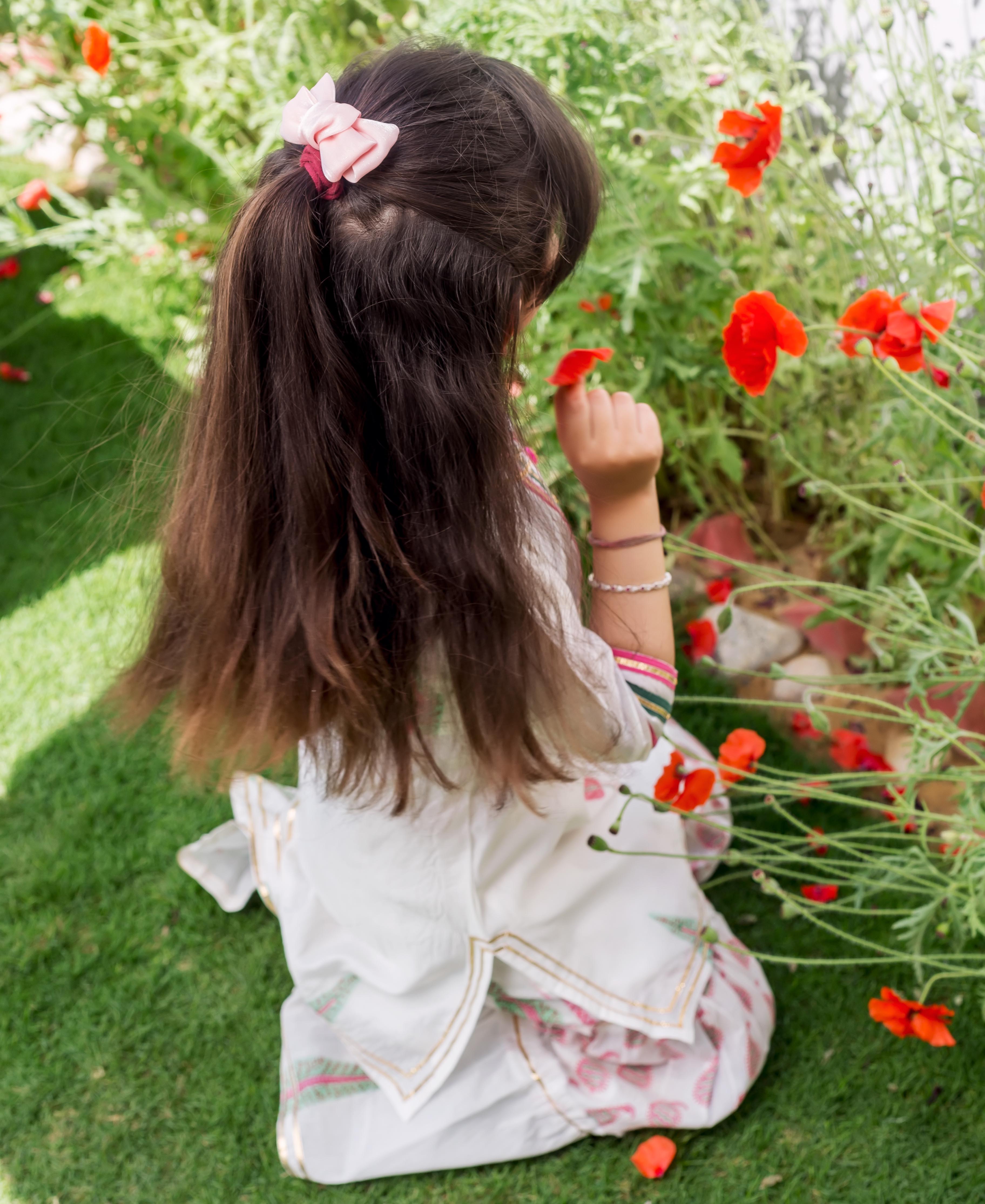 Young girl from behind in a white Chanderi hand-block printed ethnic piece with pink motifs.