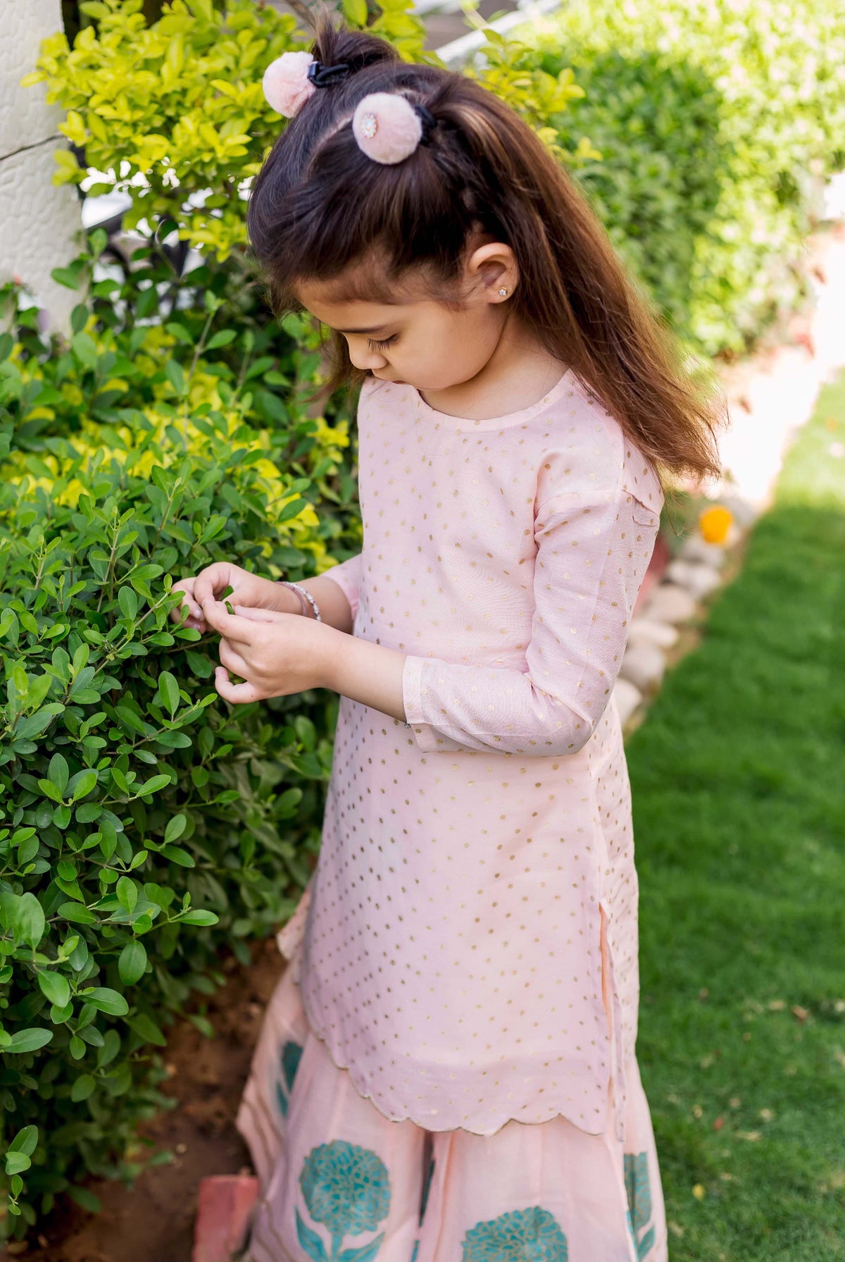 Peach polka dot printed kurta and teal block printed sharara set on young girl.