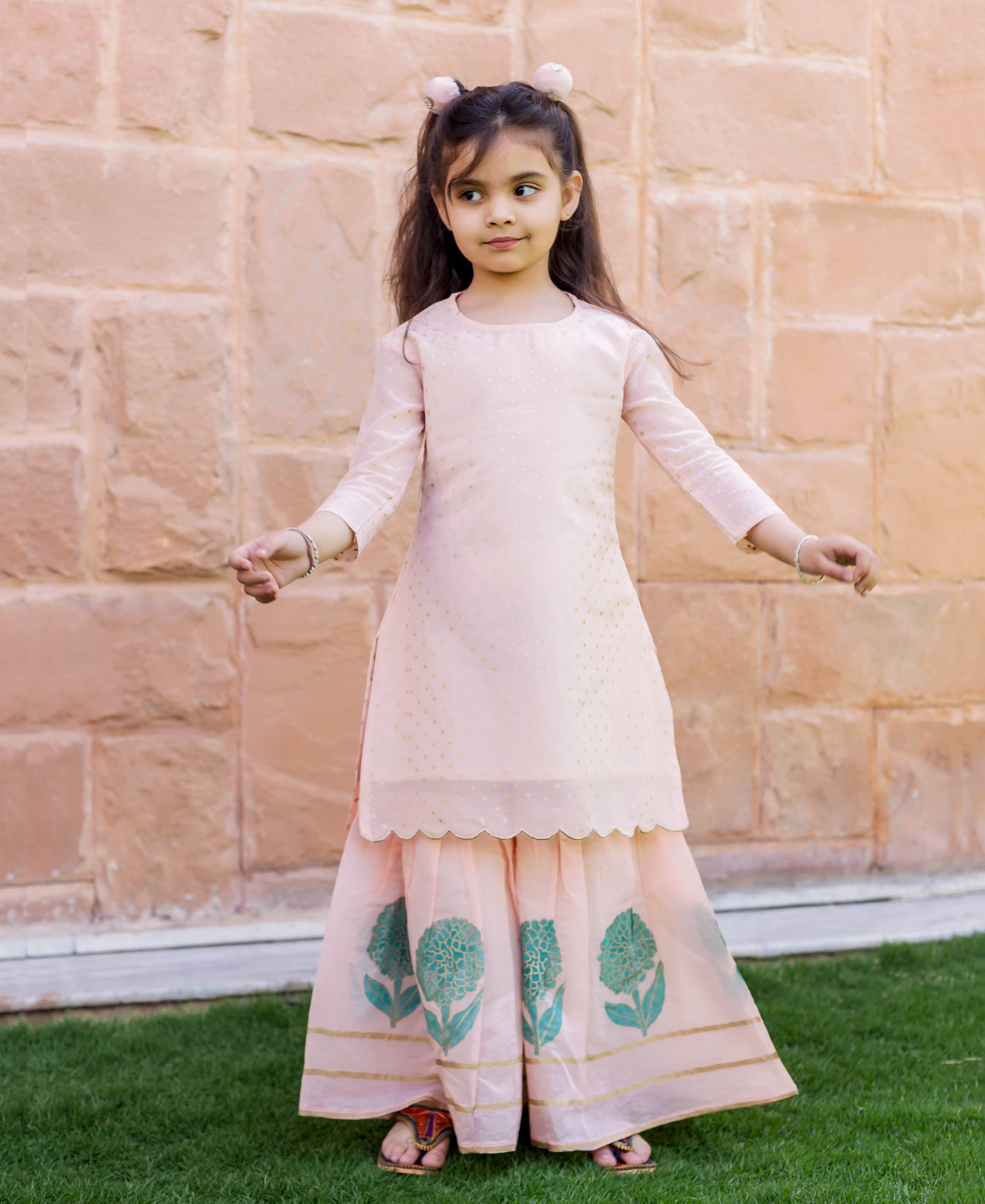 Young girl wearing a full-length peach polka dot and teal floral printed sharara set.