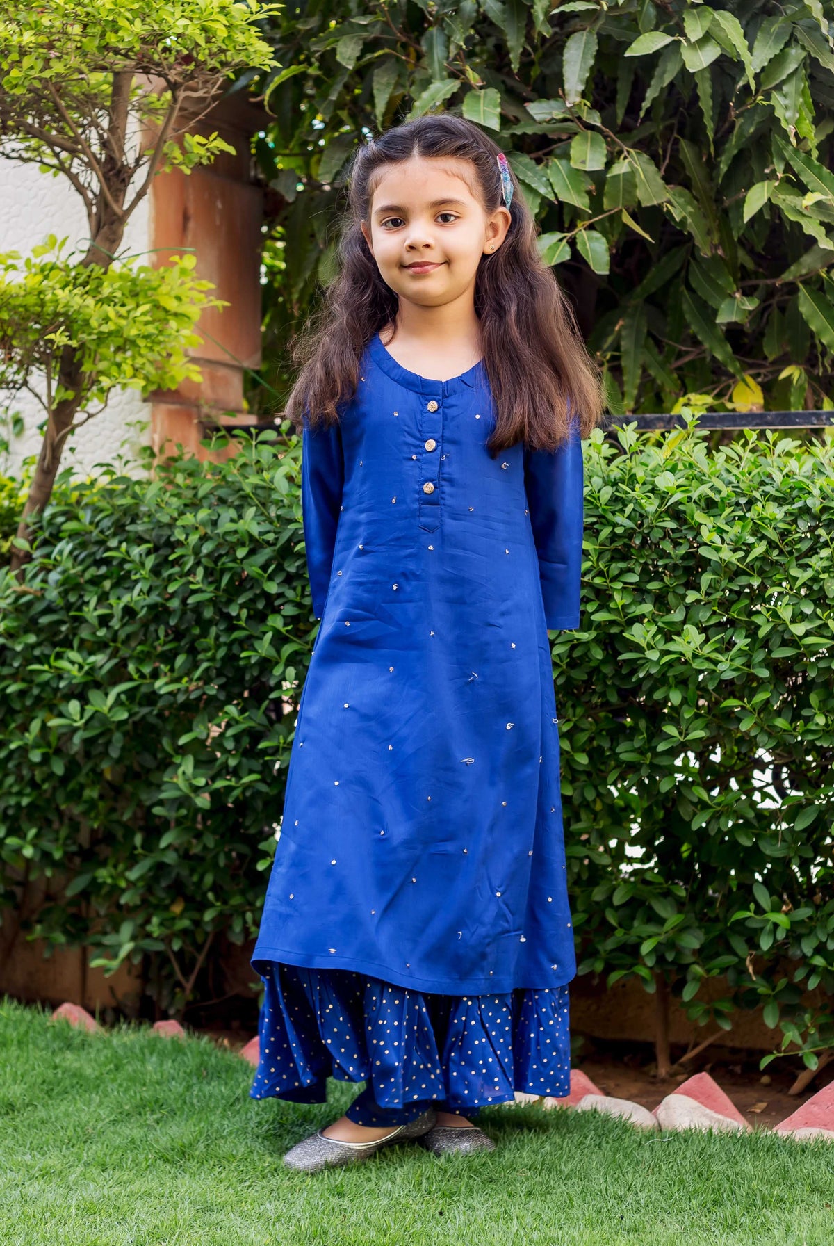 Azure blue embroidered and layered ethnic suit set on a young girl standing outdoors.