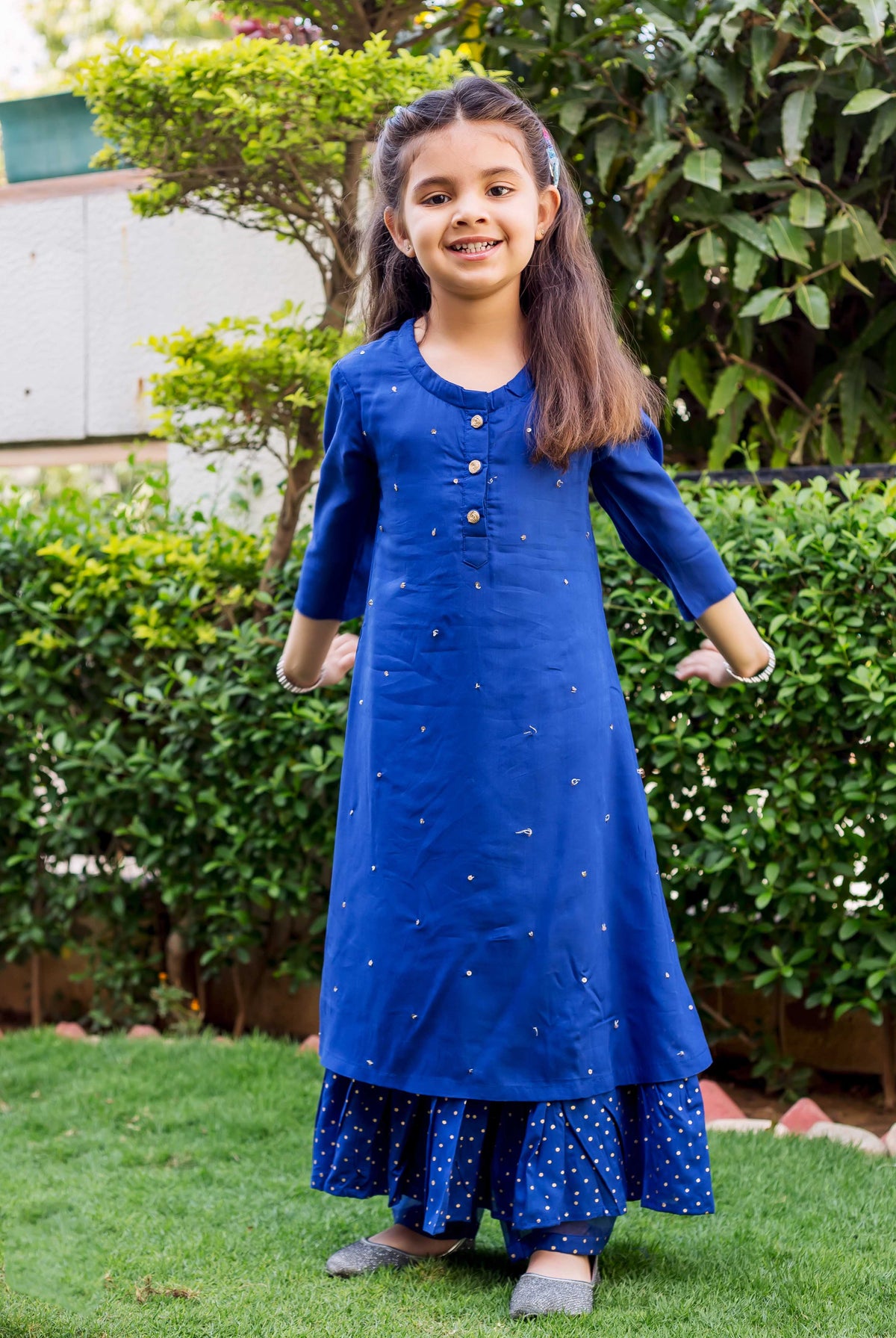 Azure blue embroidered and layered ethnic suit set on a young girl standing outdoors.