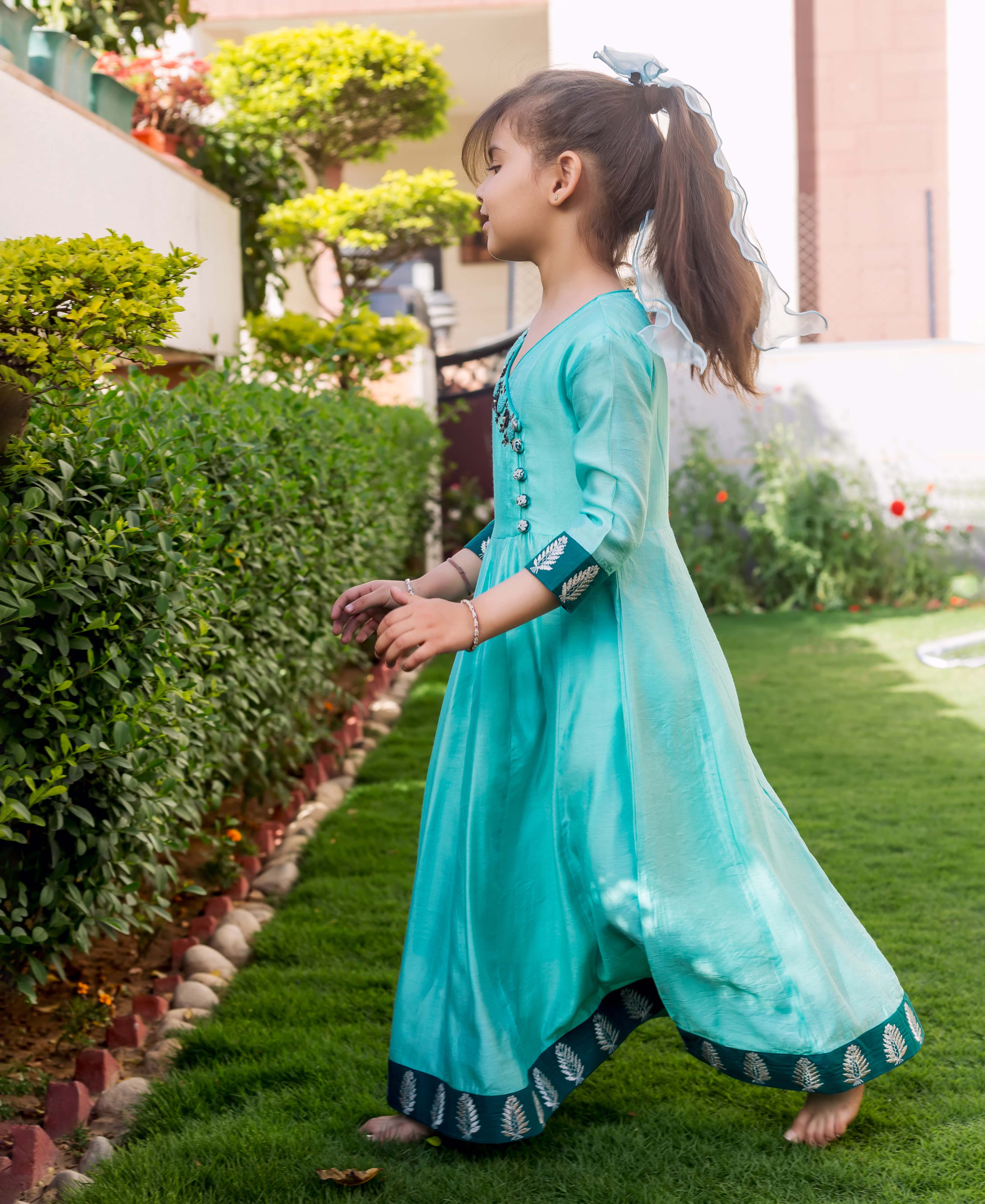 Mint green hand embroidered Angrakha dress with dark leaf-printed borders on a young girl.