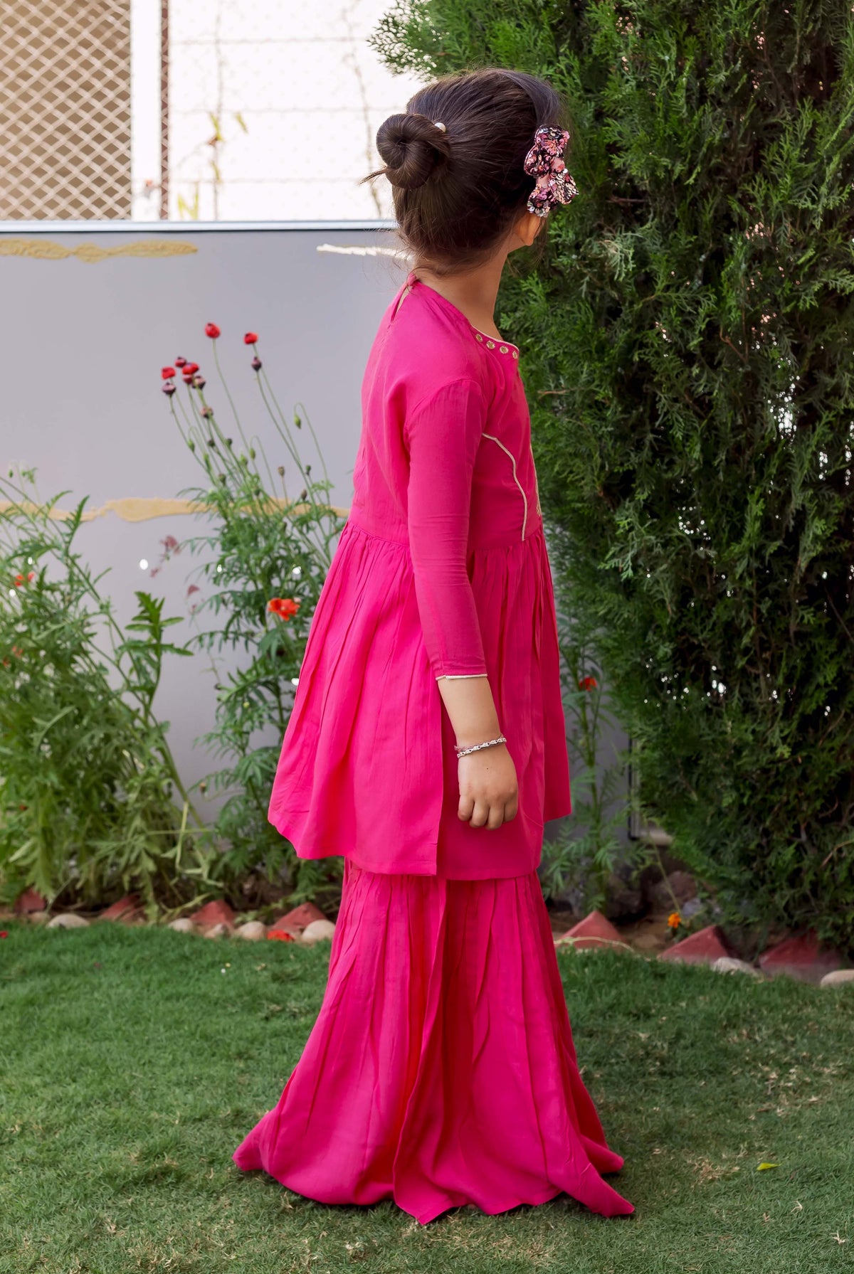 Side profile of girl in a vibrant French rose sharara set with subtle neckline embroidery.