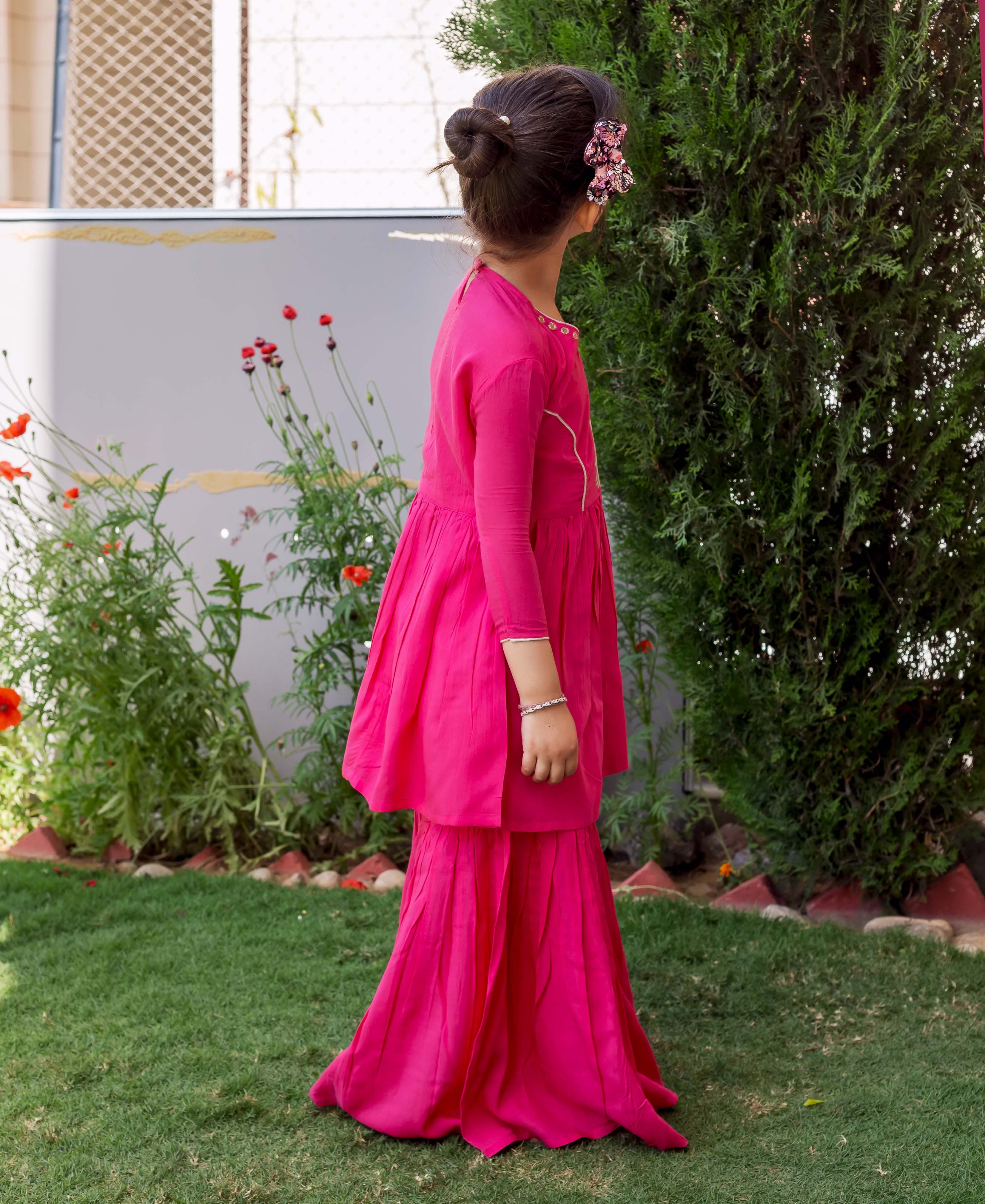 Side profile of girl in a vibrant French rose sharara set with subtle neckline embroidery.