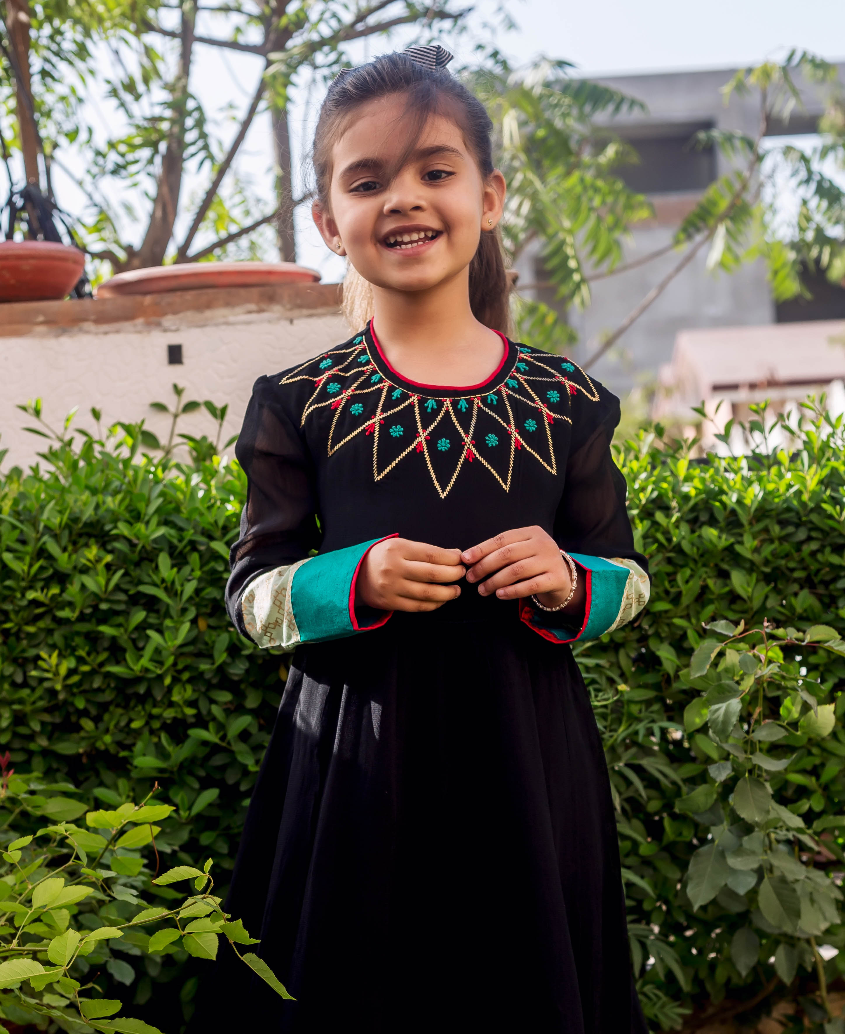 Front view: black Anarkali dress with lime, red, gold embroidered yoke and patterned cuffs.