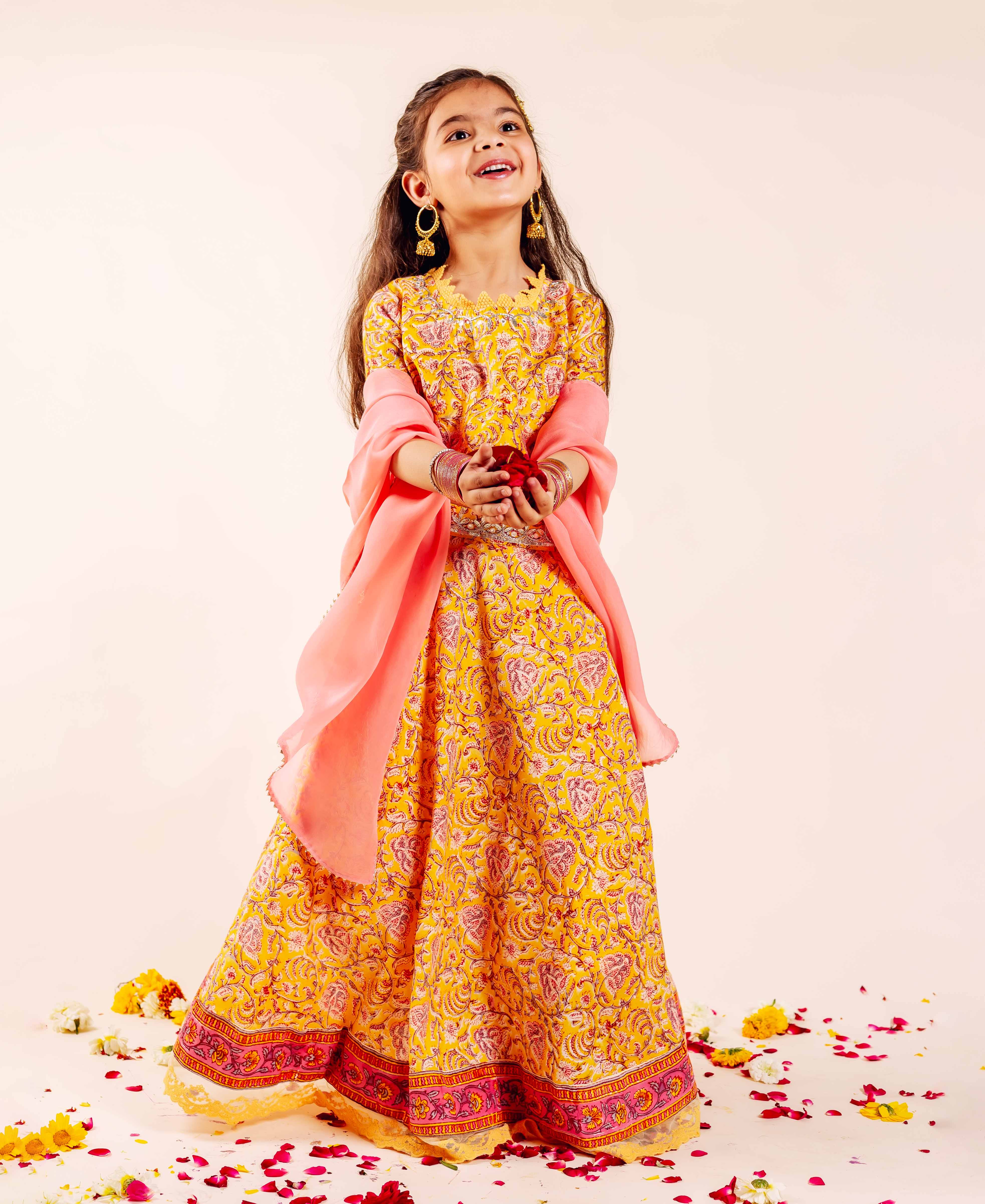 Yellow and pink hand-block-printed lehenga set on a young girl with pink dupatta.