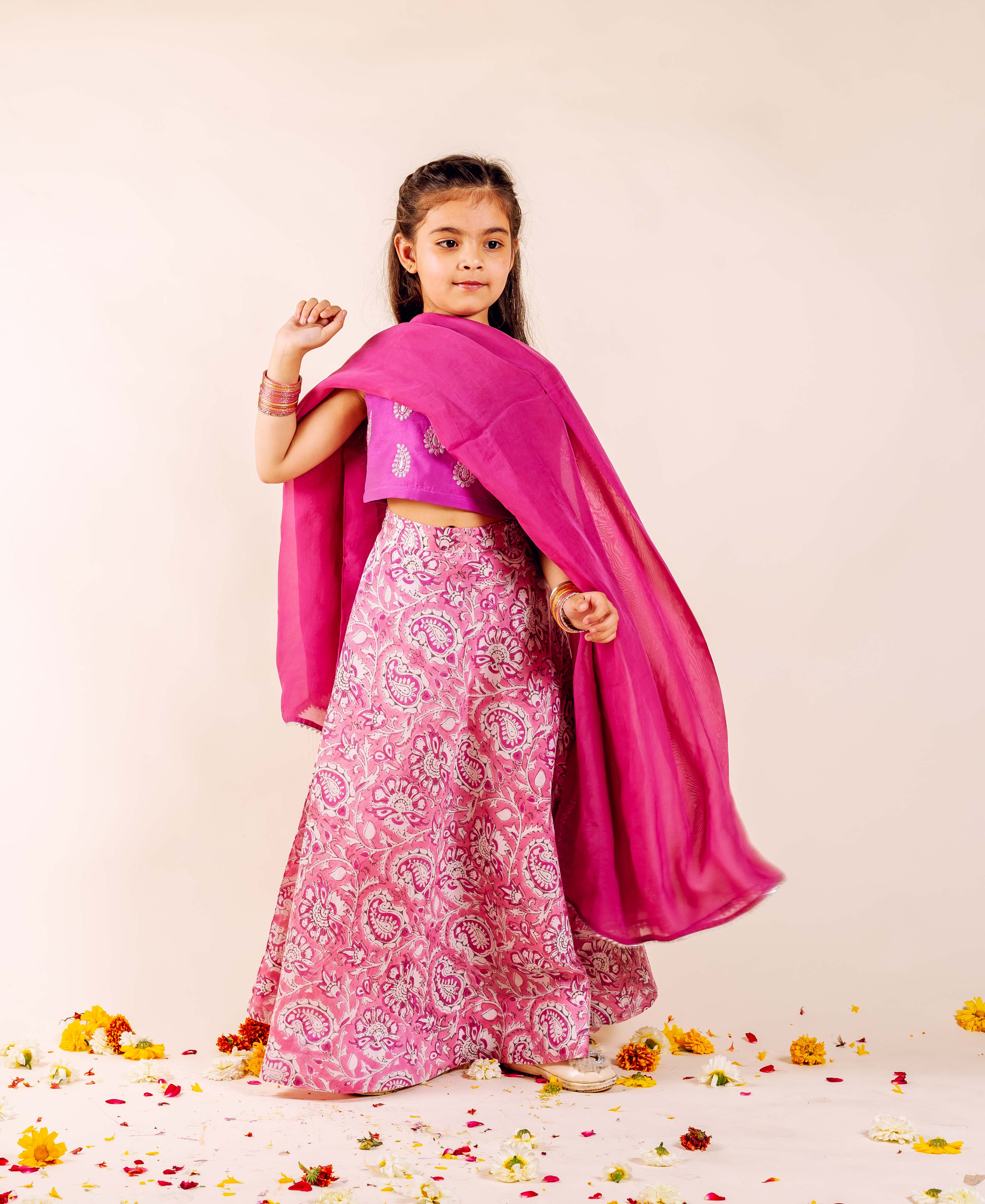 Full view of a girl in a vibrant pink hand-block-printed lehenga set and dupatta.