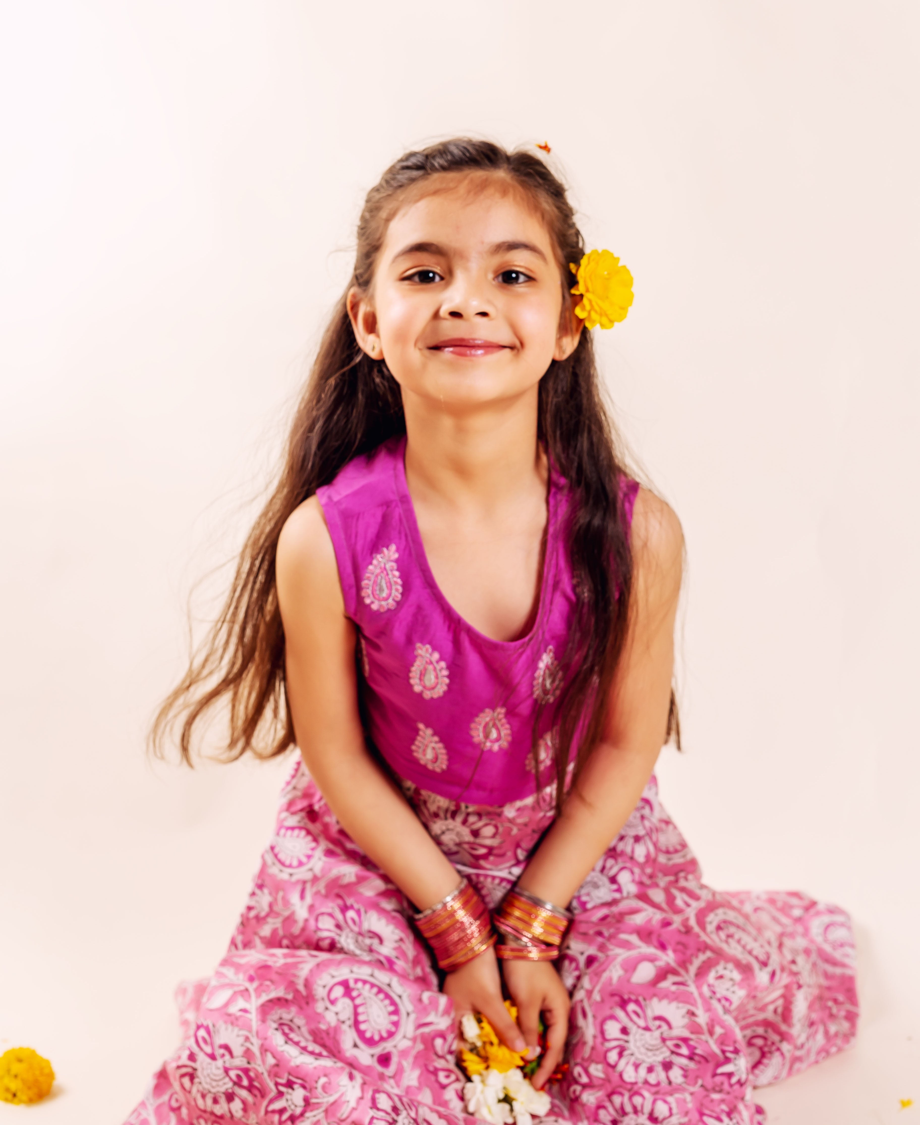 Baby girl wearing a vibrant magenta and pink paisley hand-block print lehenga set.
