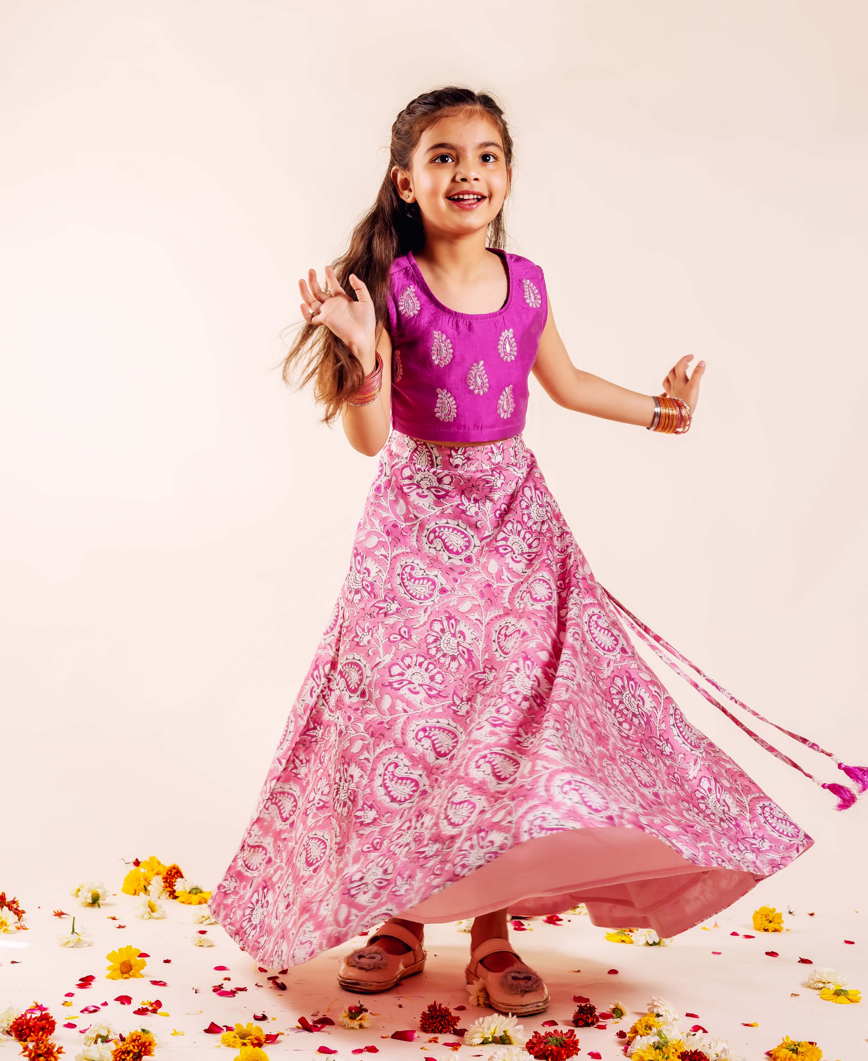 Pink and white hand-block-printed lehenga set with gold accents on magenta top and flowing skirt.