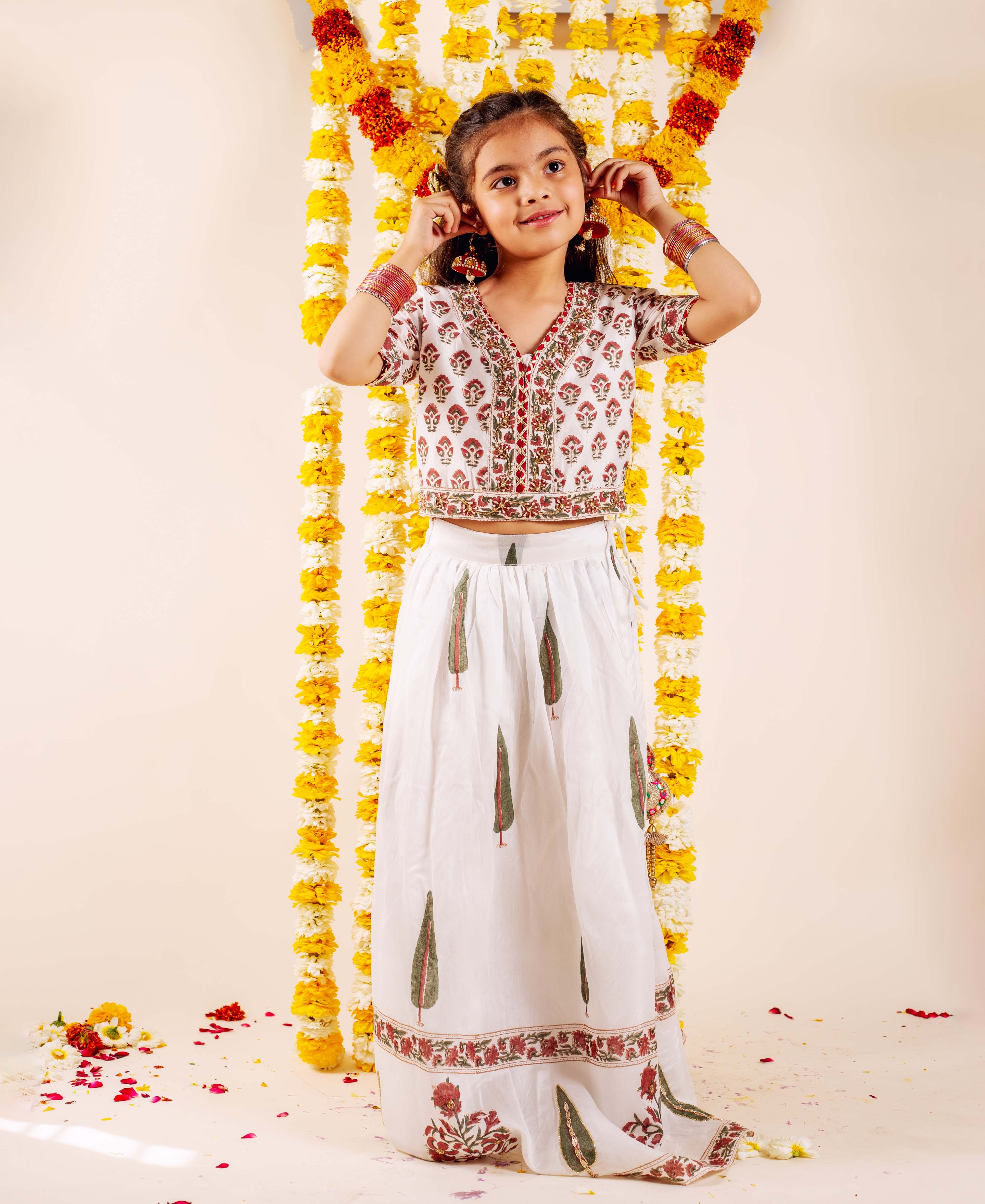 Girl in white, red, and green embroidered hand-block print lehenga set, full-body.