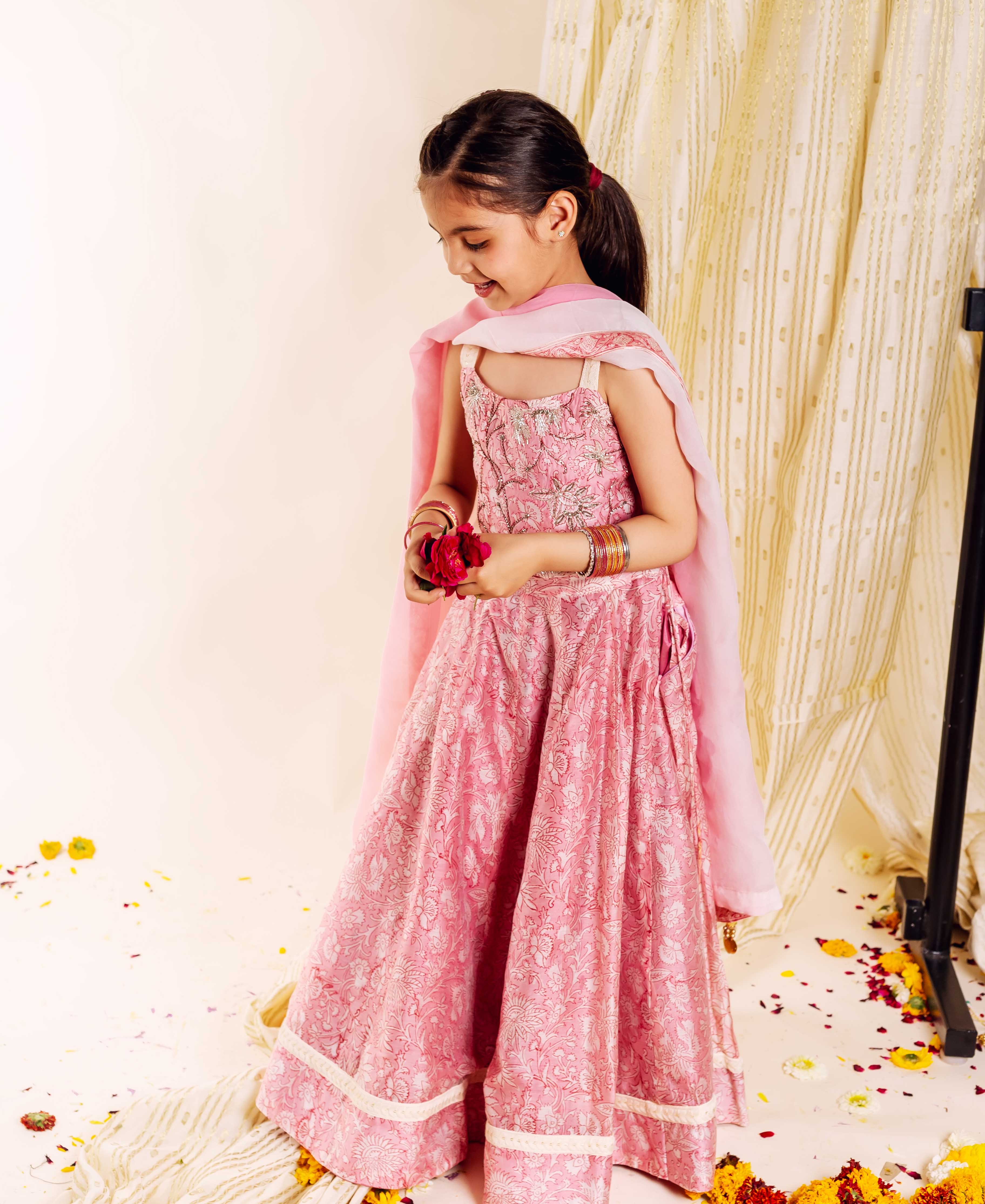Young girl models a pink hand-block-printed floral lehenga set with a light pink dupatta.