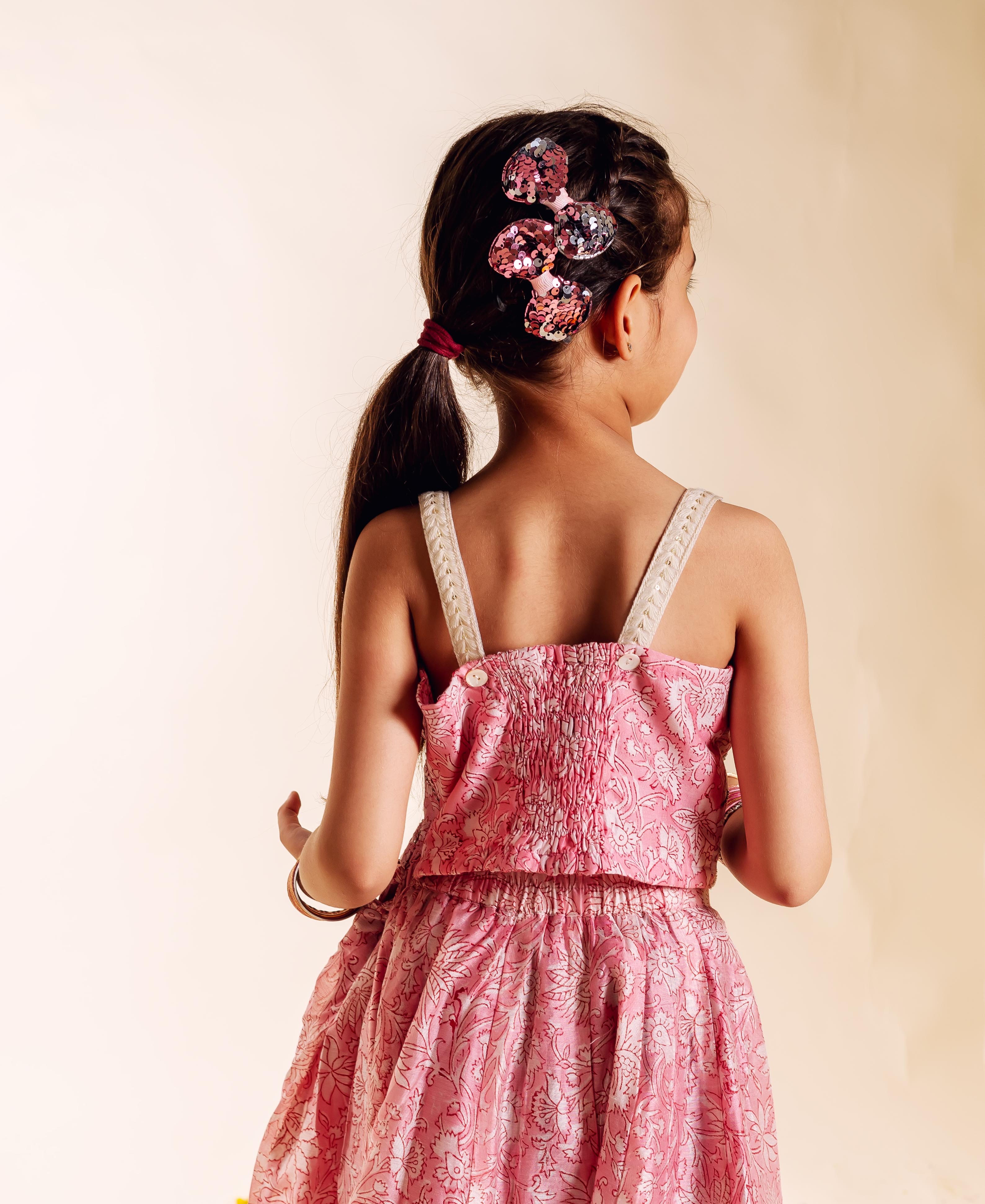 Back view of a young girl in a pink floral print dress with sequined hair clips.