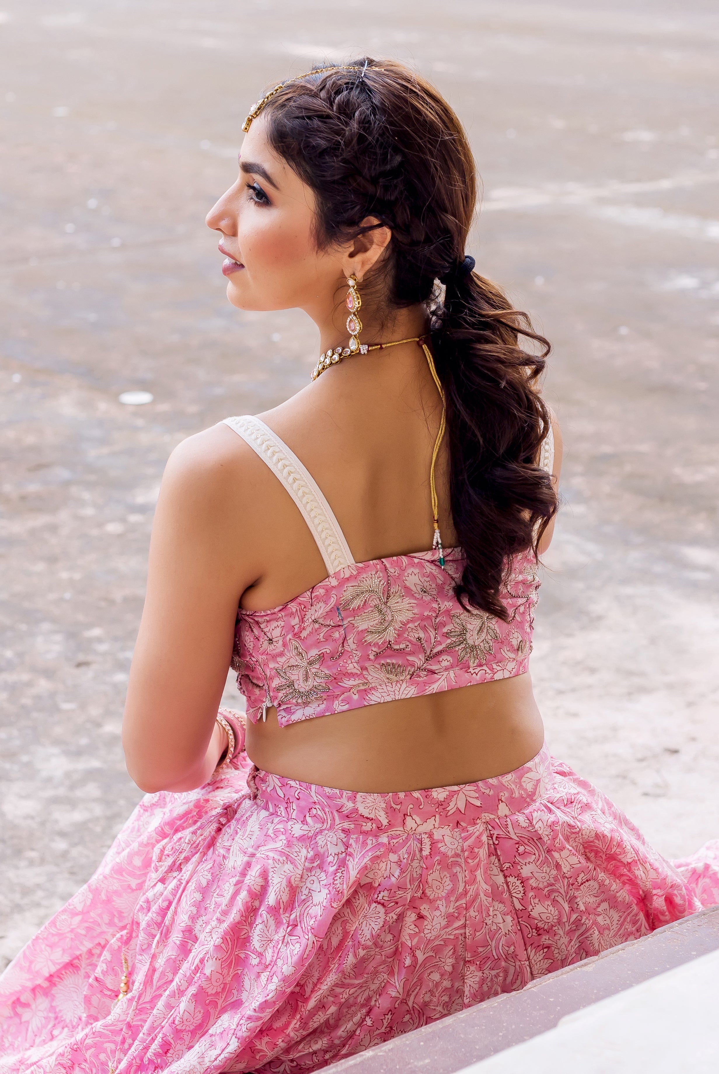 Pink hand block printed, embroidered lehenga set on model, back profile, with white floral patterns.