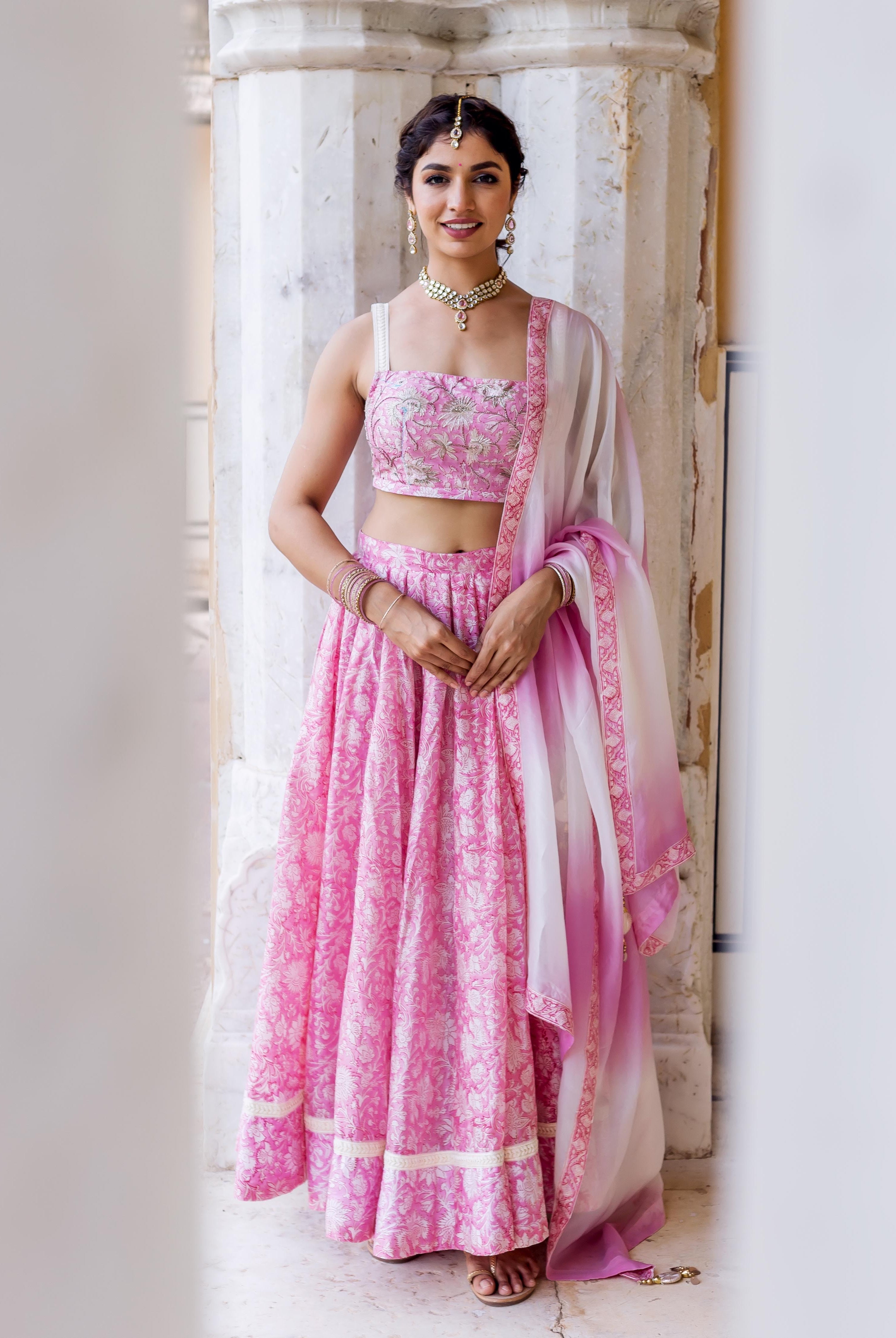 A woman in a pink and white floral lehenga set with a matching dupatta.