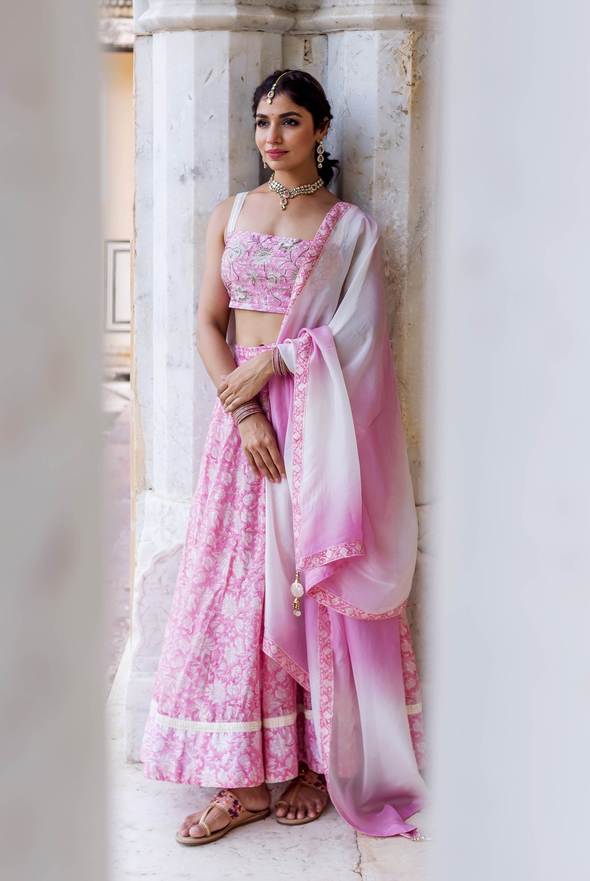 Full-length model in pink and white floral Mahi hand-block printed embroidered lehenga set.