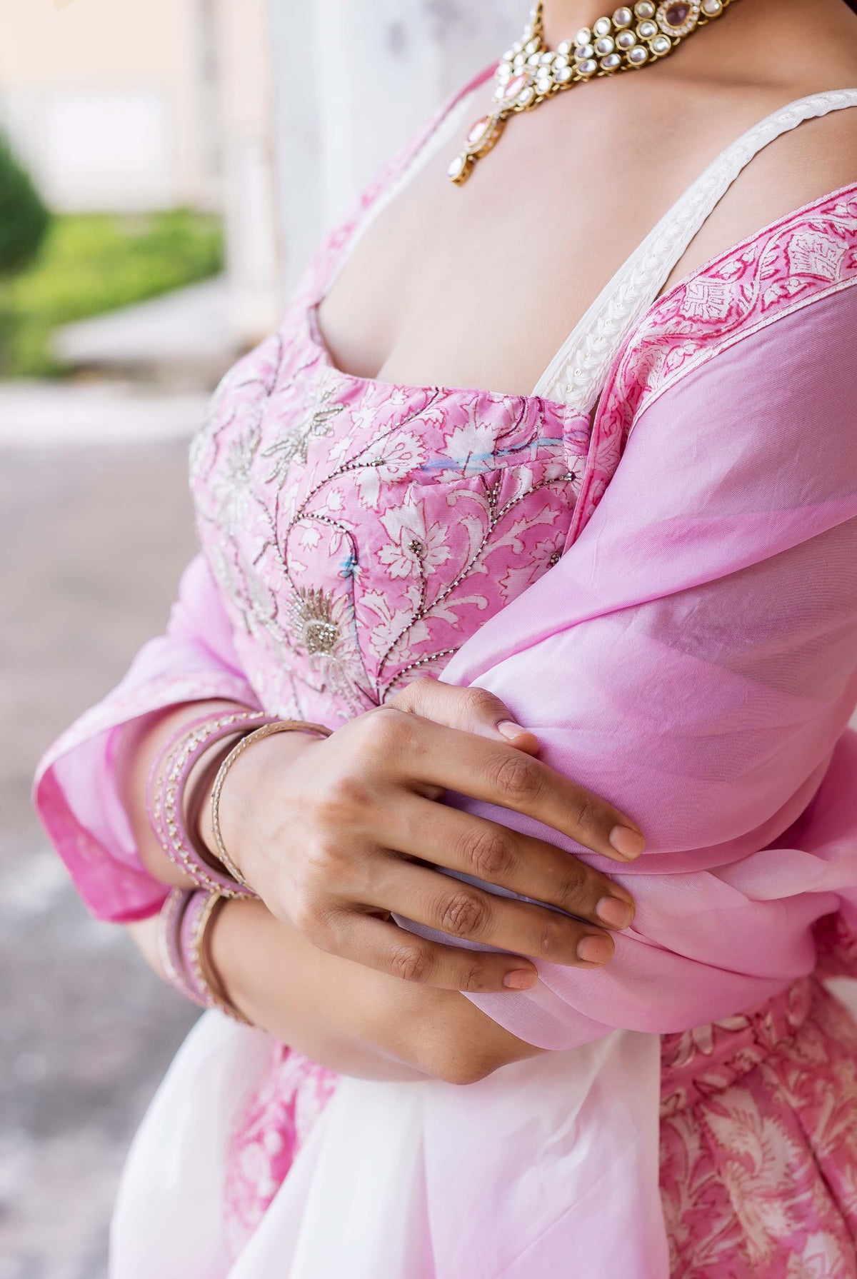 Close-up of a model in a pink embroidered hand-block printed lehenga set and gold necklace.