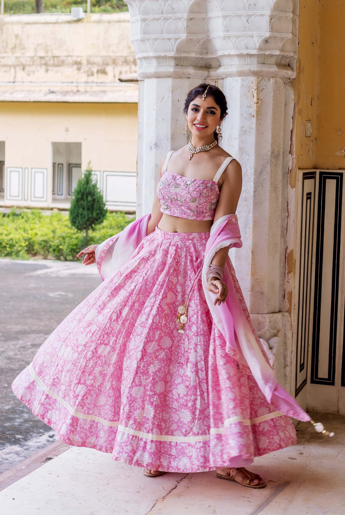 Smiling model in a flowing pink hand block printed lehenga set with dupatta.