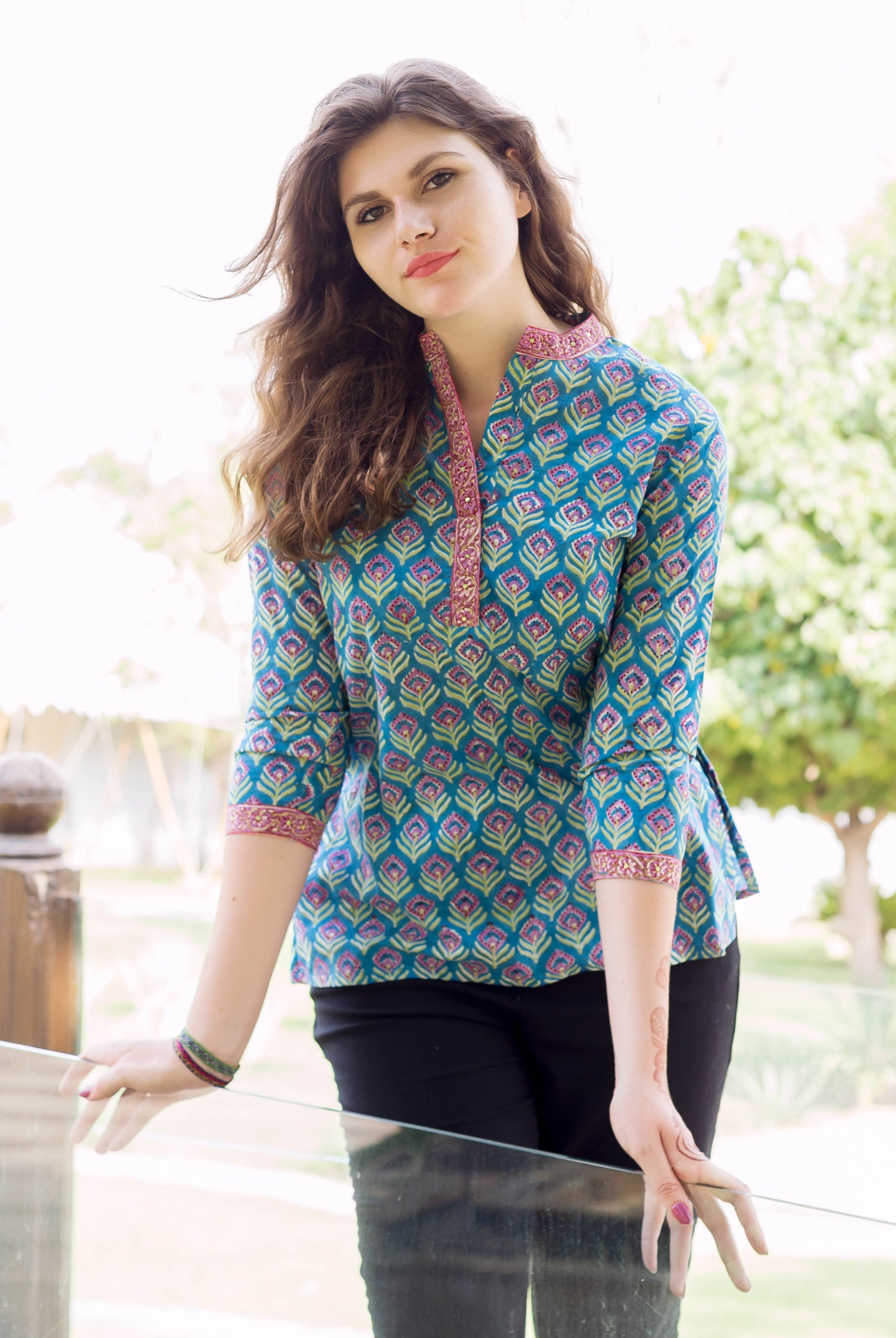 Front view model wears teal hand block printed ethnic top with peacock-like pattern.