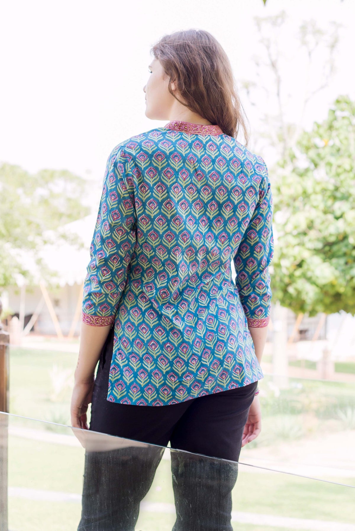 Back view of model in blue ethnic top with vibrant pink-green hand block print pattern.