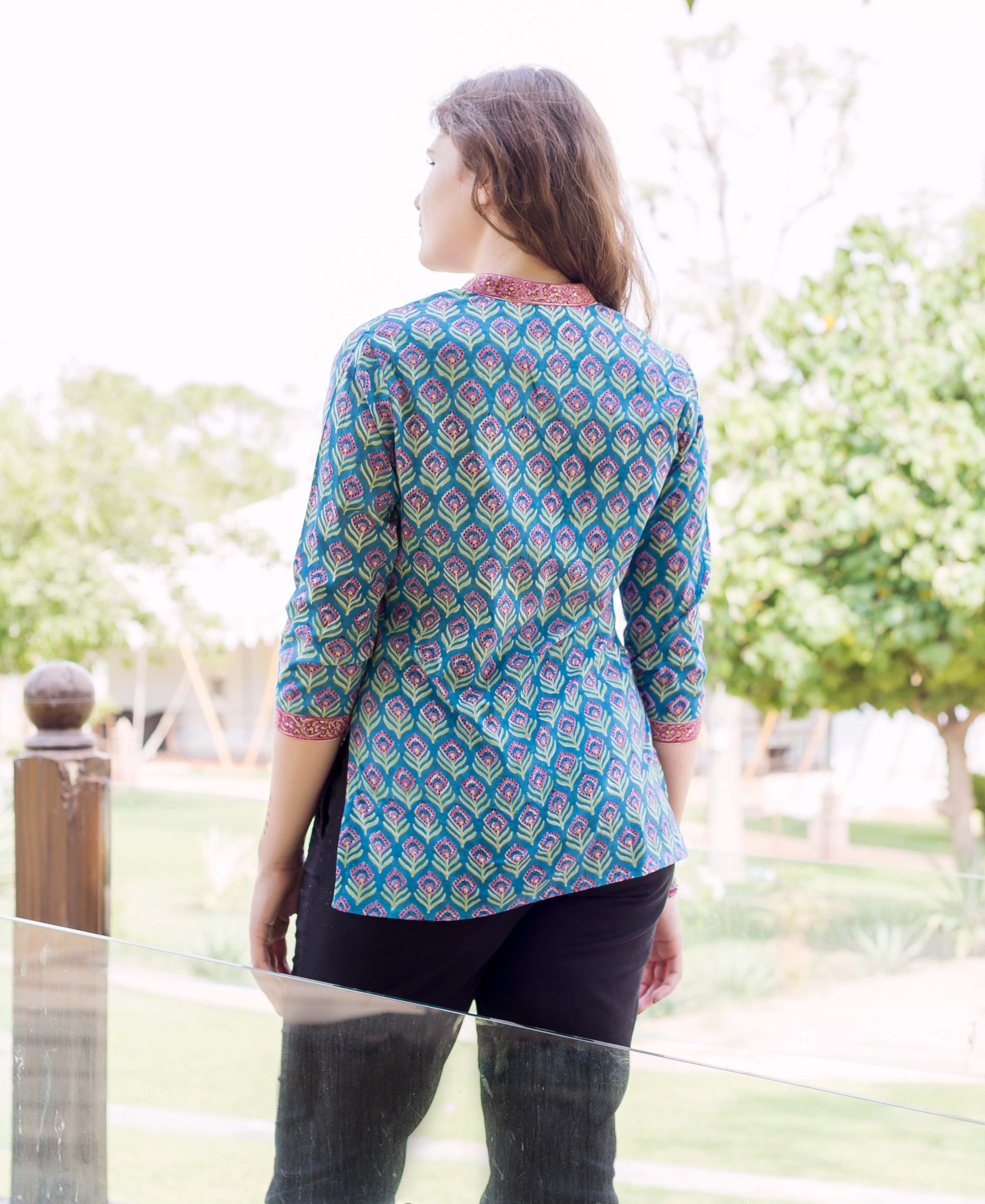 Back view of model in blue ethnic top with vibrant pink-green hand block print pattern.