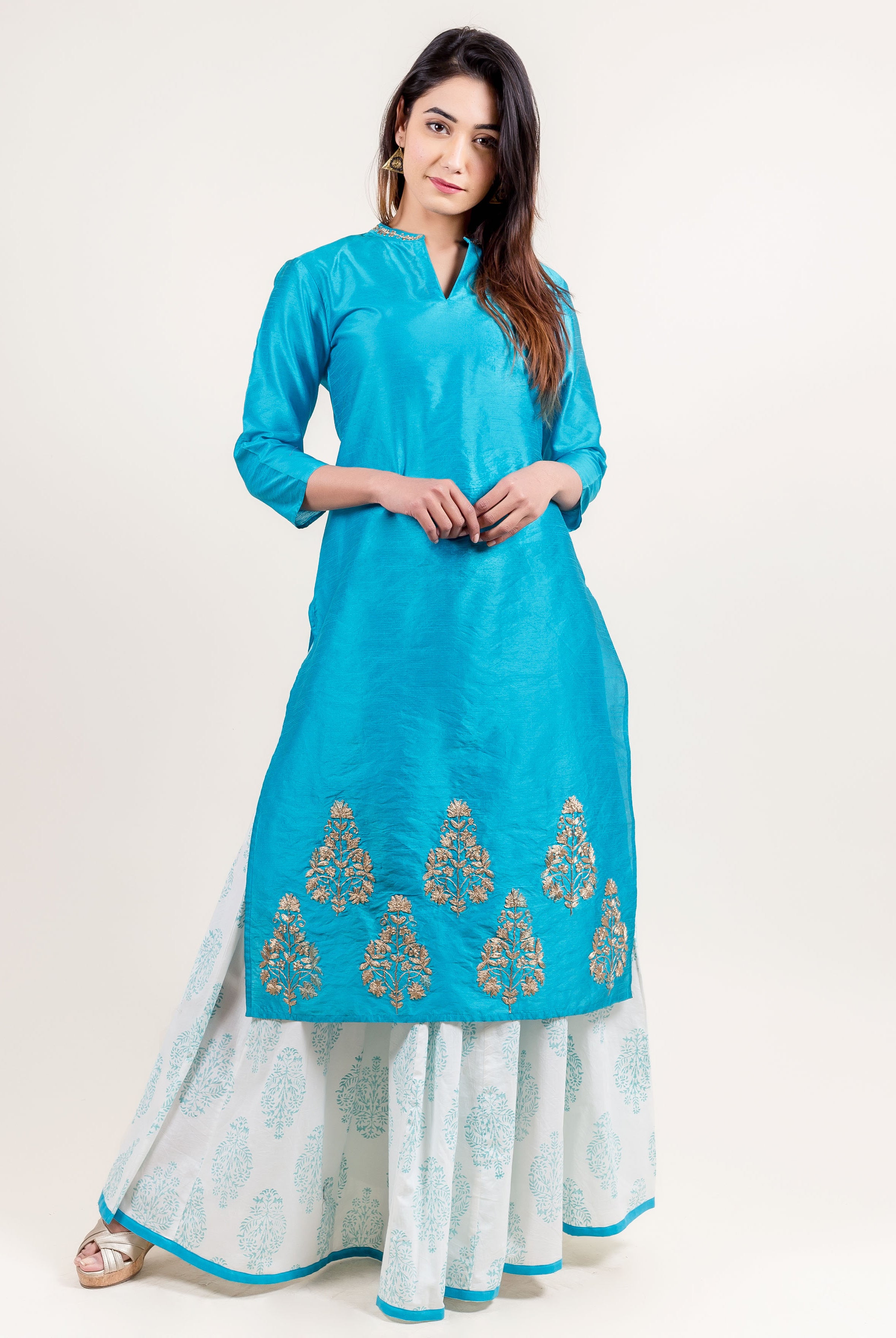 Turquoise kurta with gold embroidery and white palazzo pants with turquoise floral print hem.