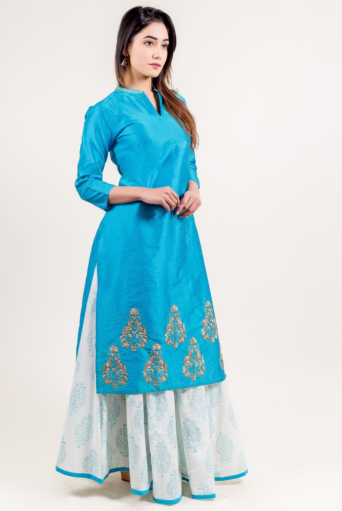 Bright blue embroidered kurta worn by woman over white block-printed flared skirt.