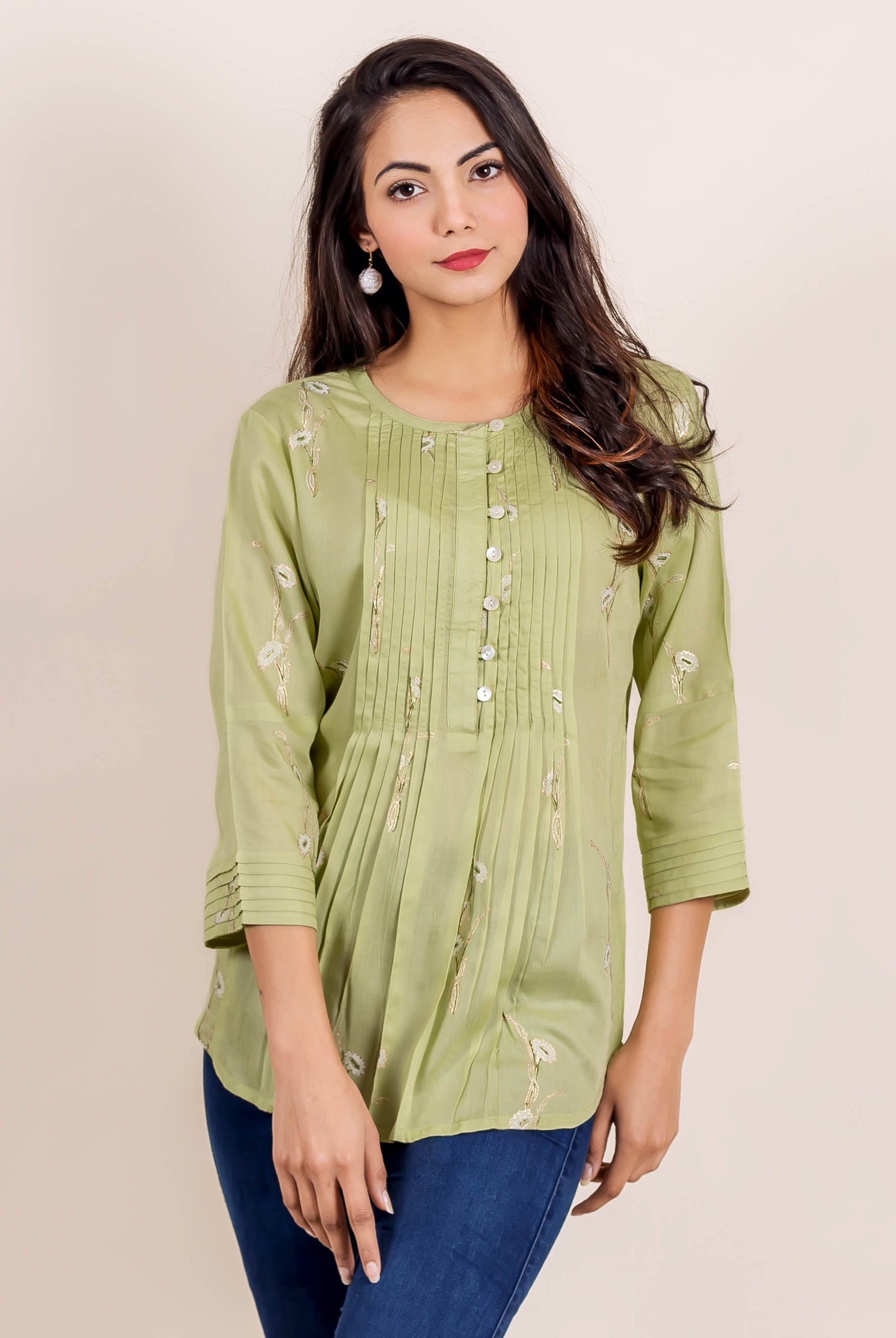 Front view of model in a green hand block printed pleated top with white floral design.