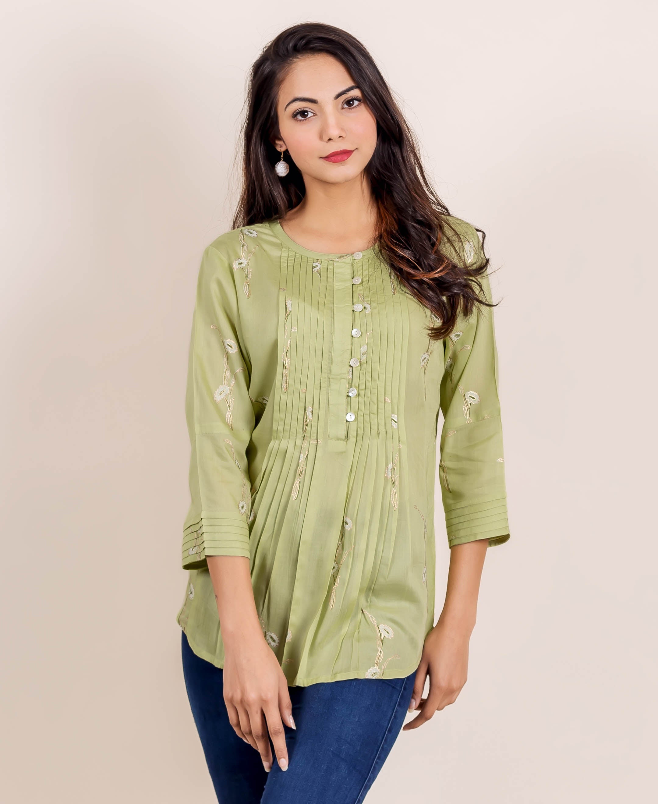 Front view of model in a green hand block printed pleated top with white floral design.
