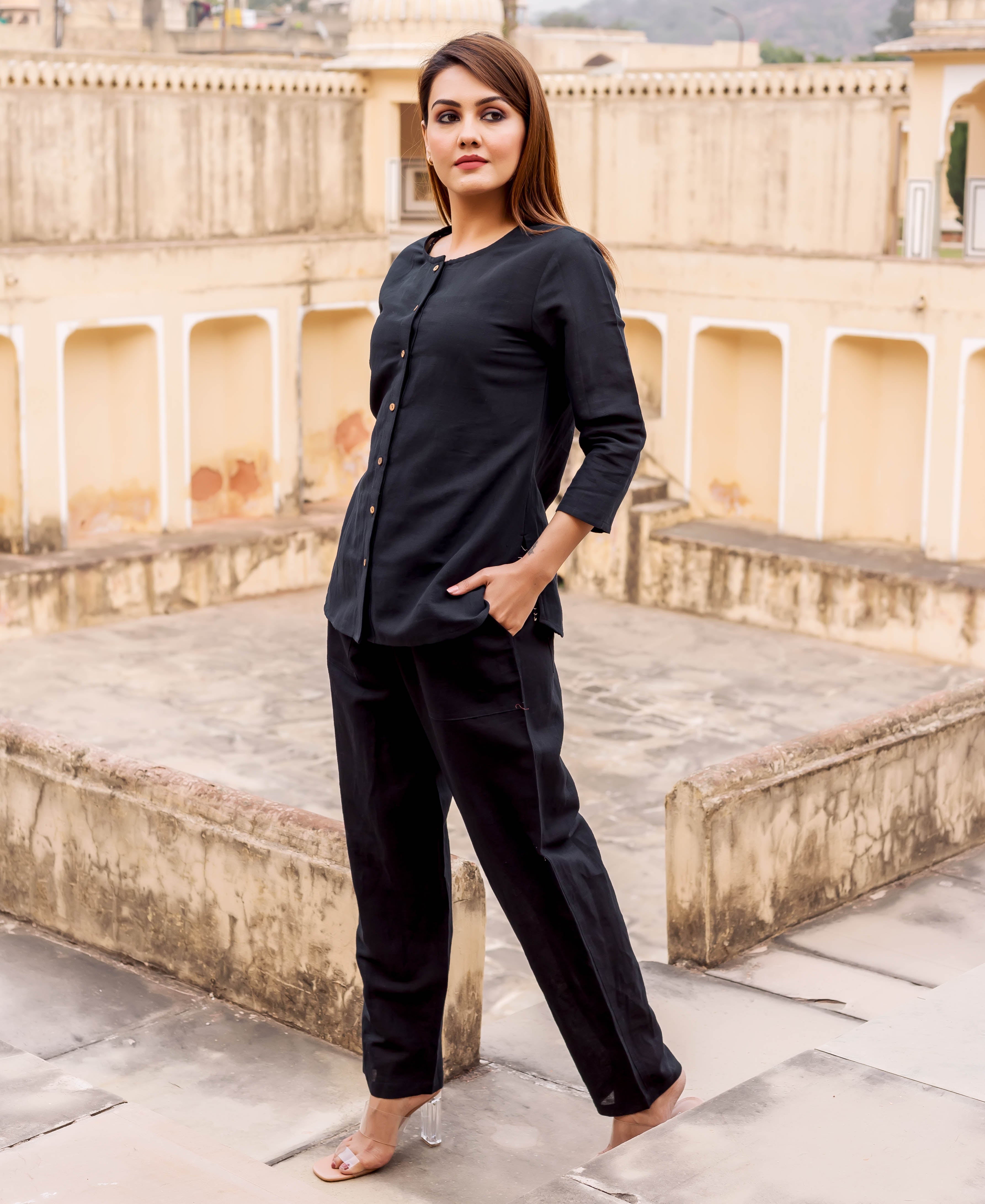 Model, front view, wearing a full black linen ensemble with a buttoned top and matching pants.