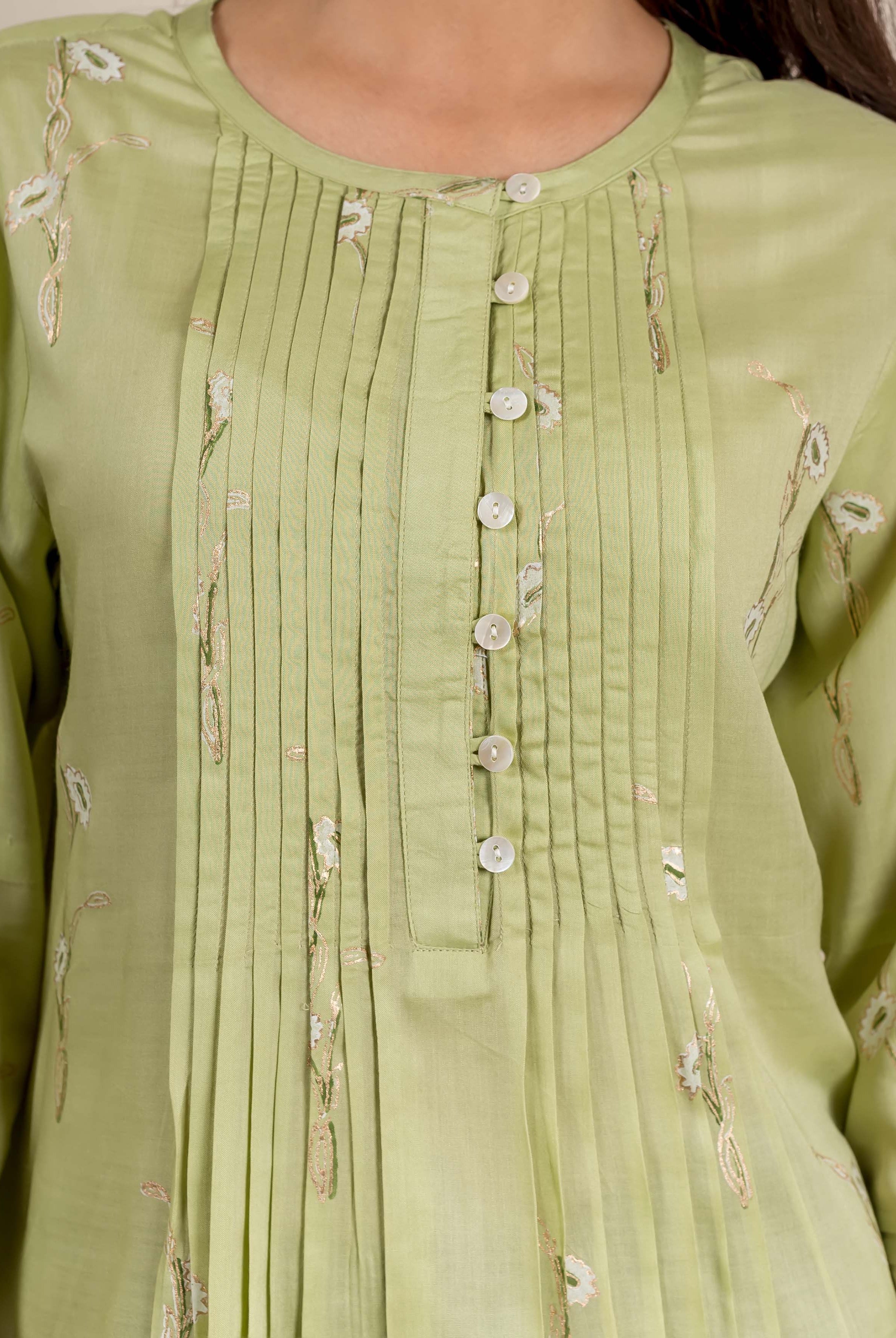 A model wears a green, hand-block-printed, pleated top with floral patterns.