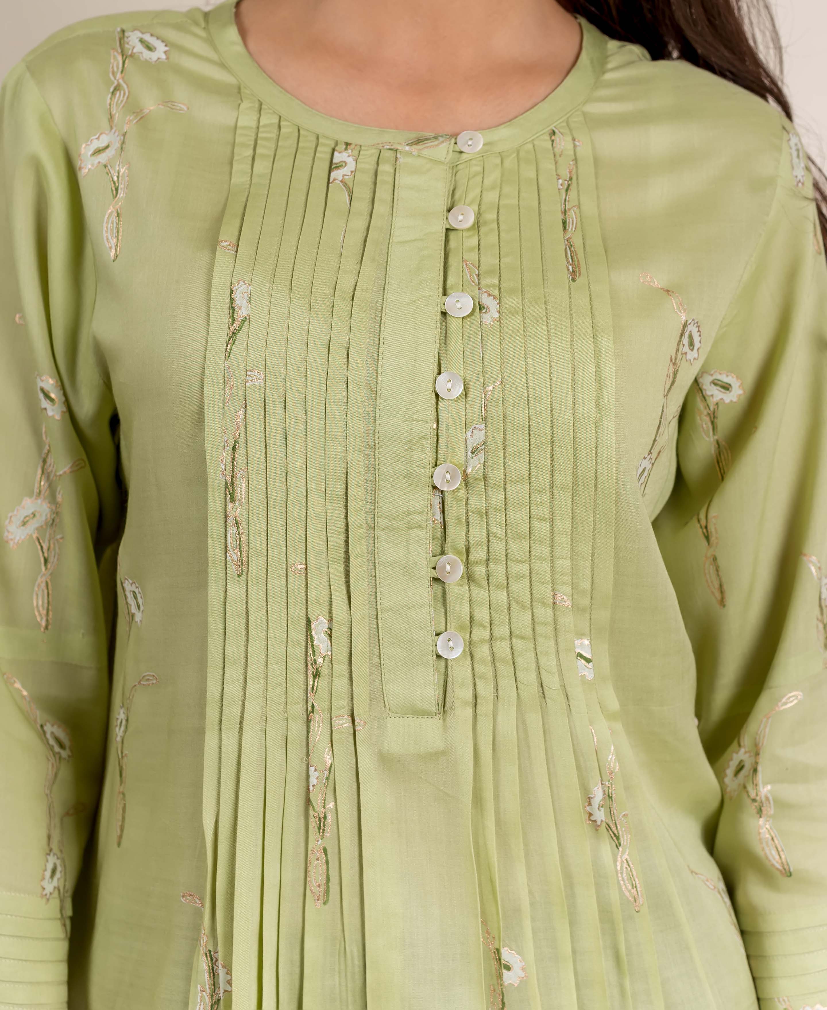 A model wears a green, hand-block-printed, pleated top with floral patterns.