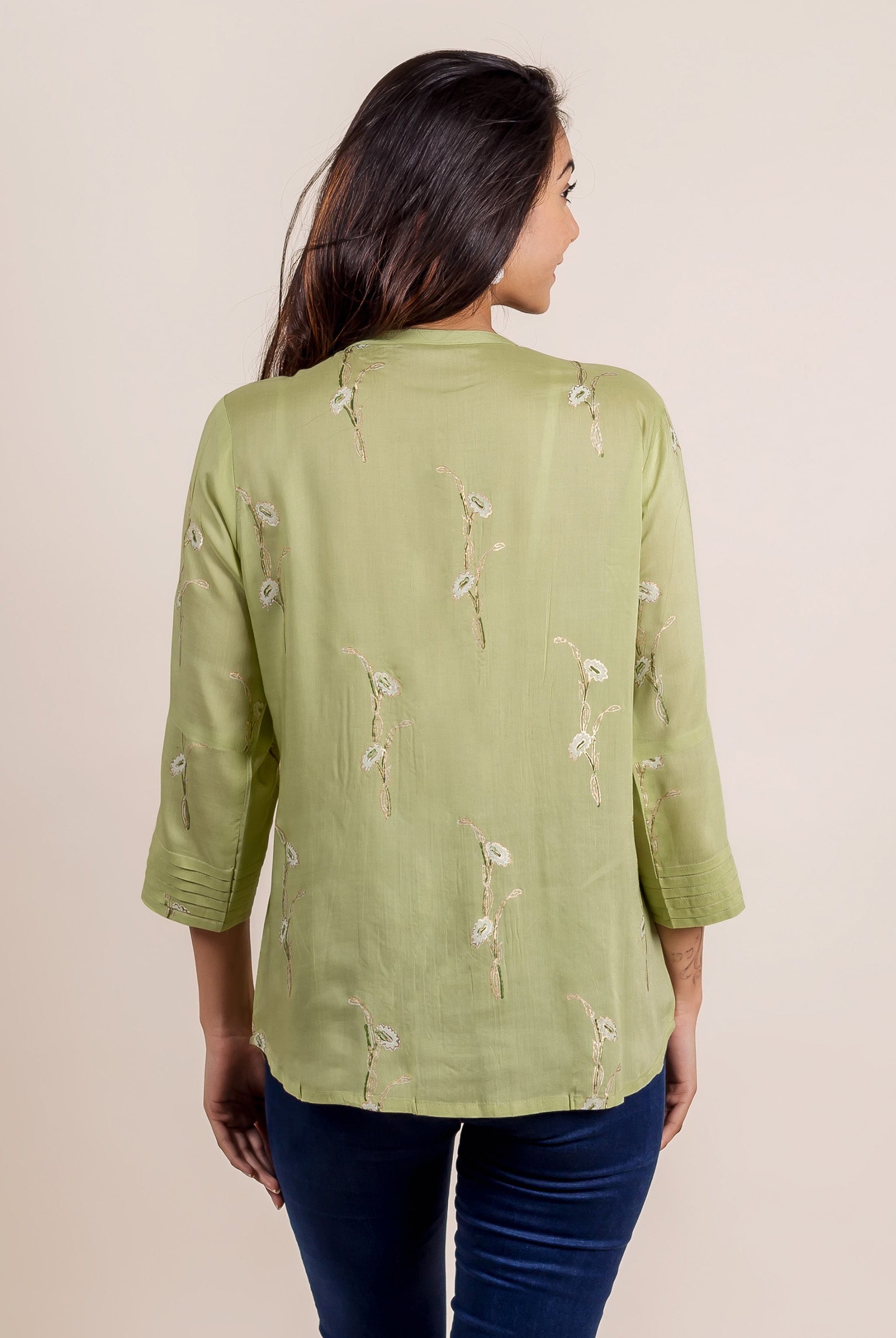 Back view of model in green hand-block printed top with white floral motifs and pleated sleeves.