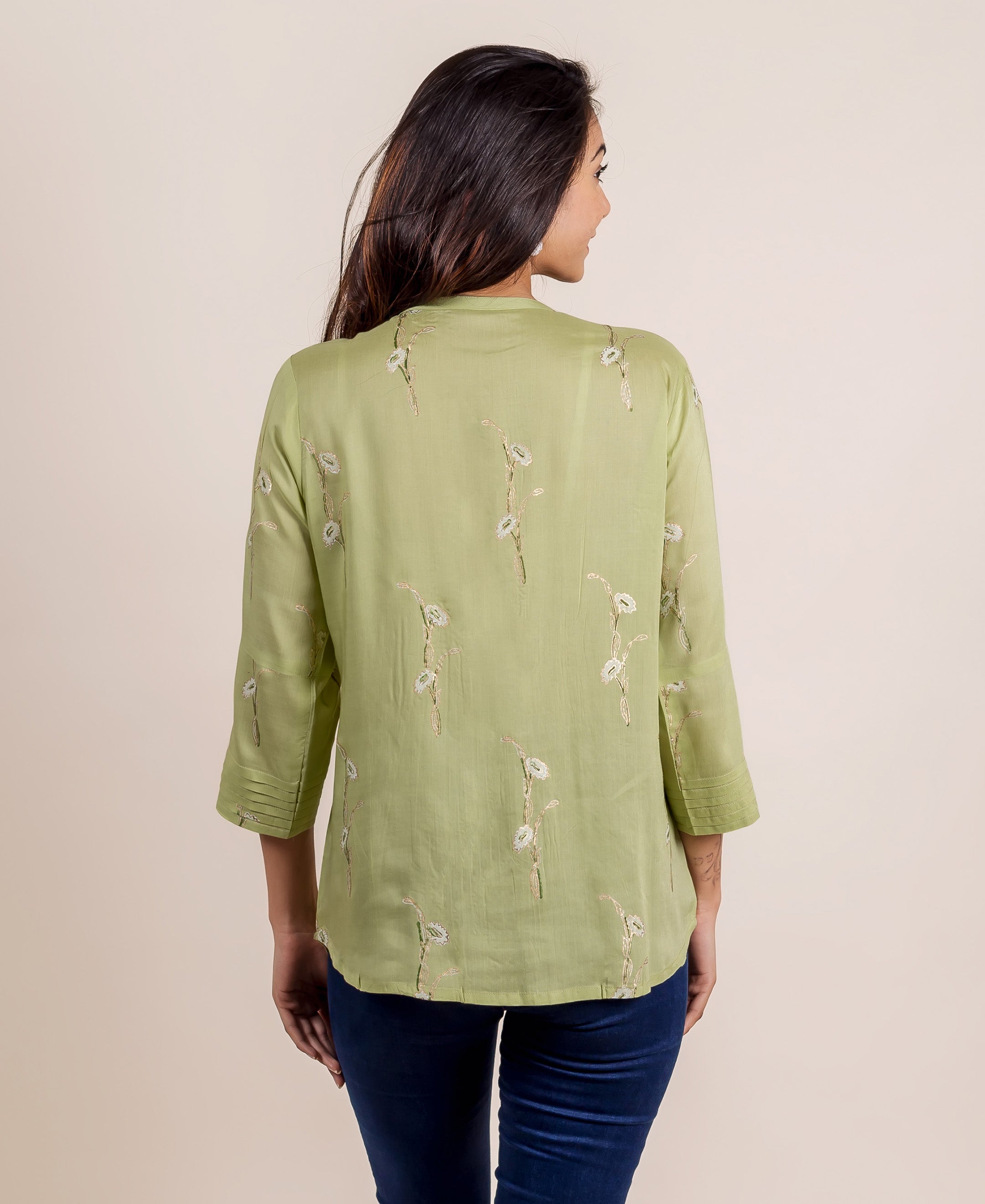 Back view of model in green hand-block printed top with white floral motifs and pleated sleeves.
