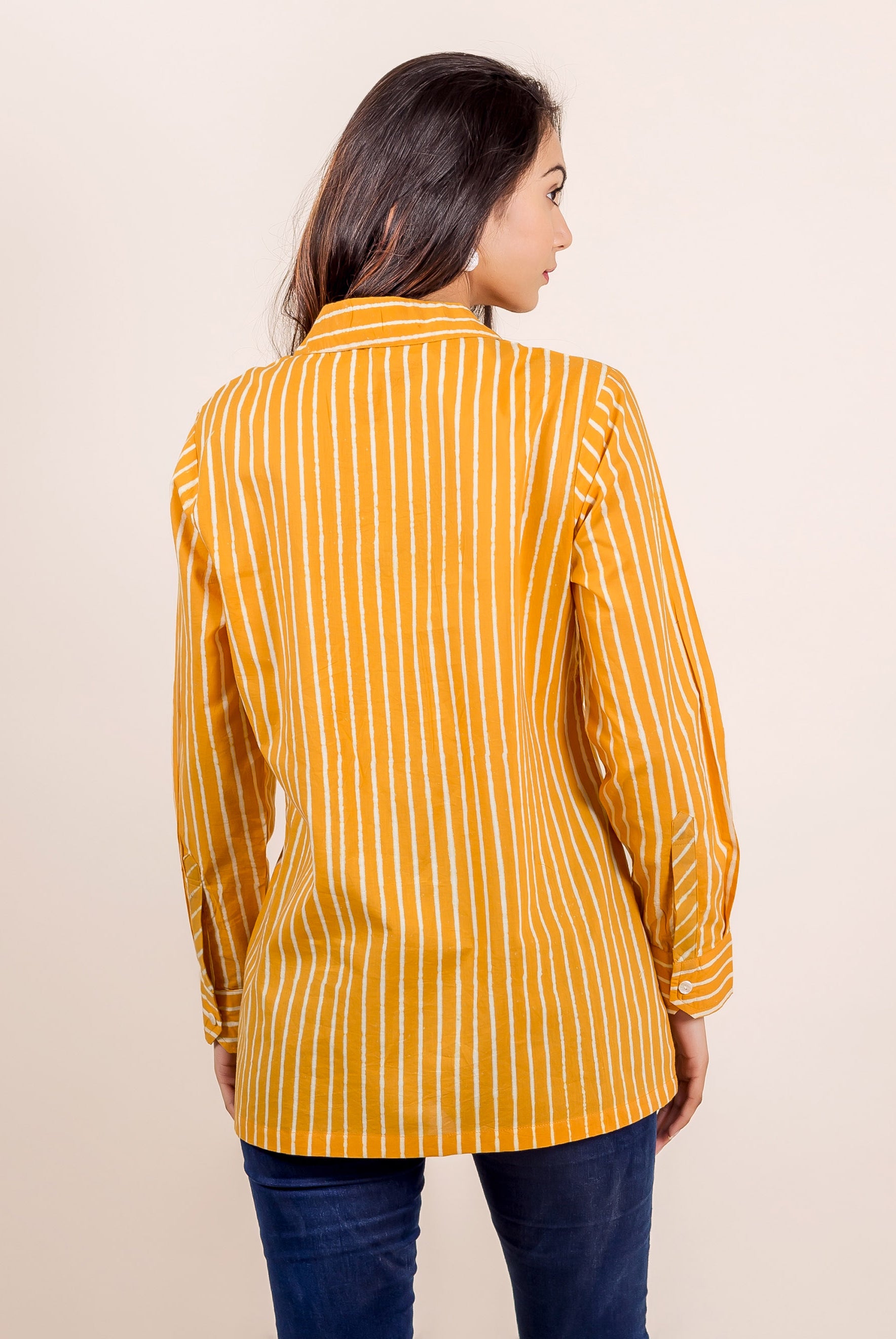 Rear view of model wearing yellow hand-block printed striped long-sleeved shirt top.