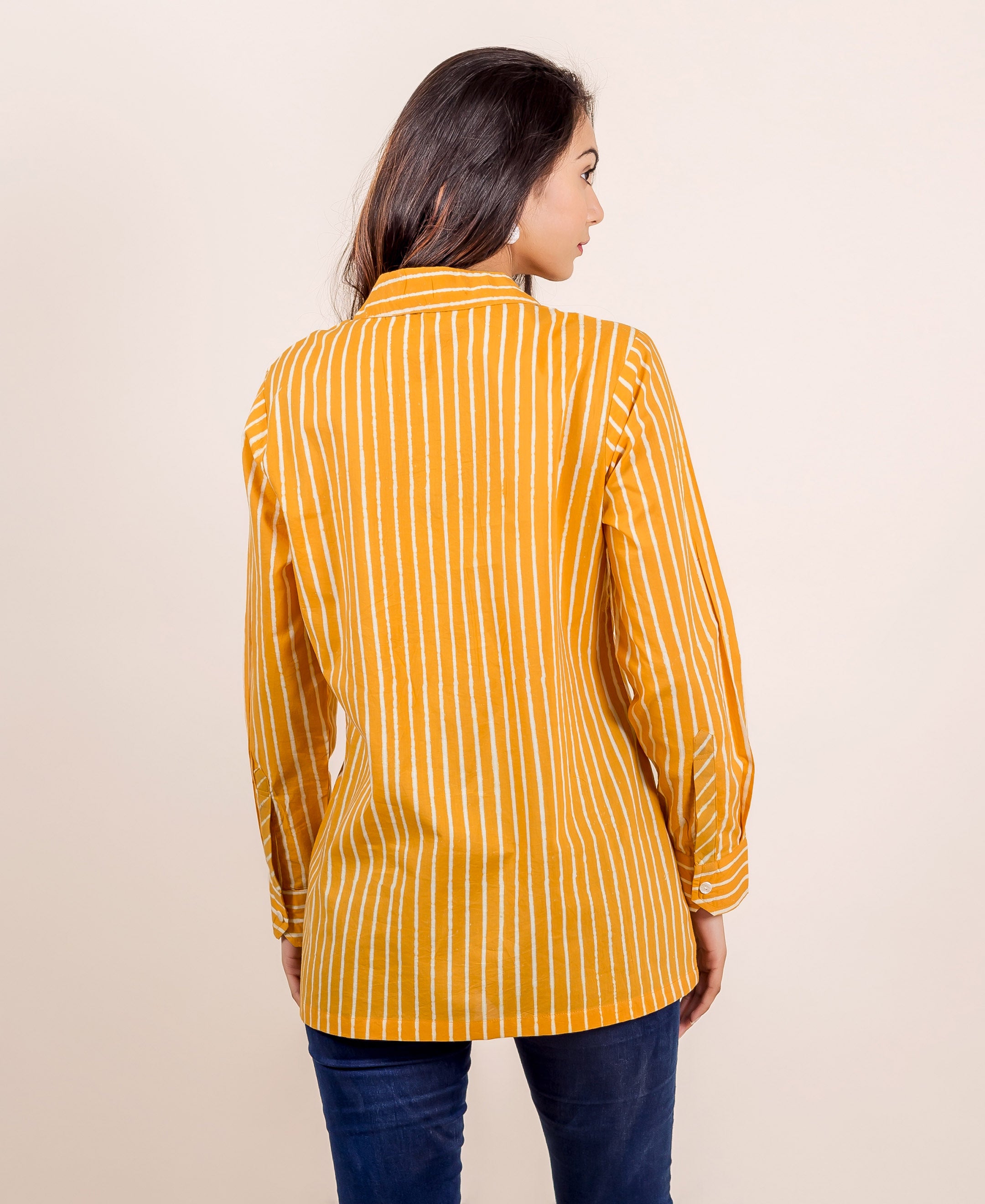 Rear view of model wearing yellow hand-block printed striped long-sleeved shirt top.